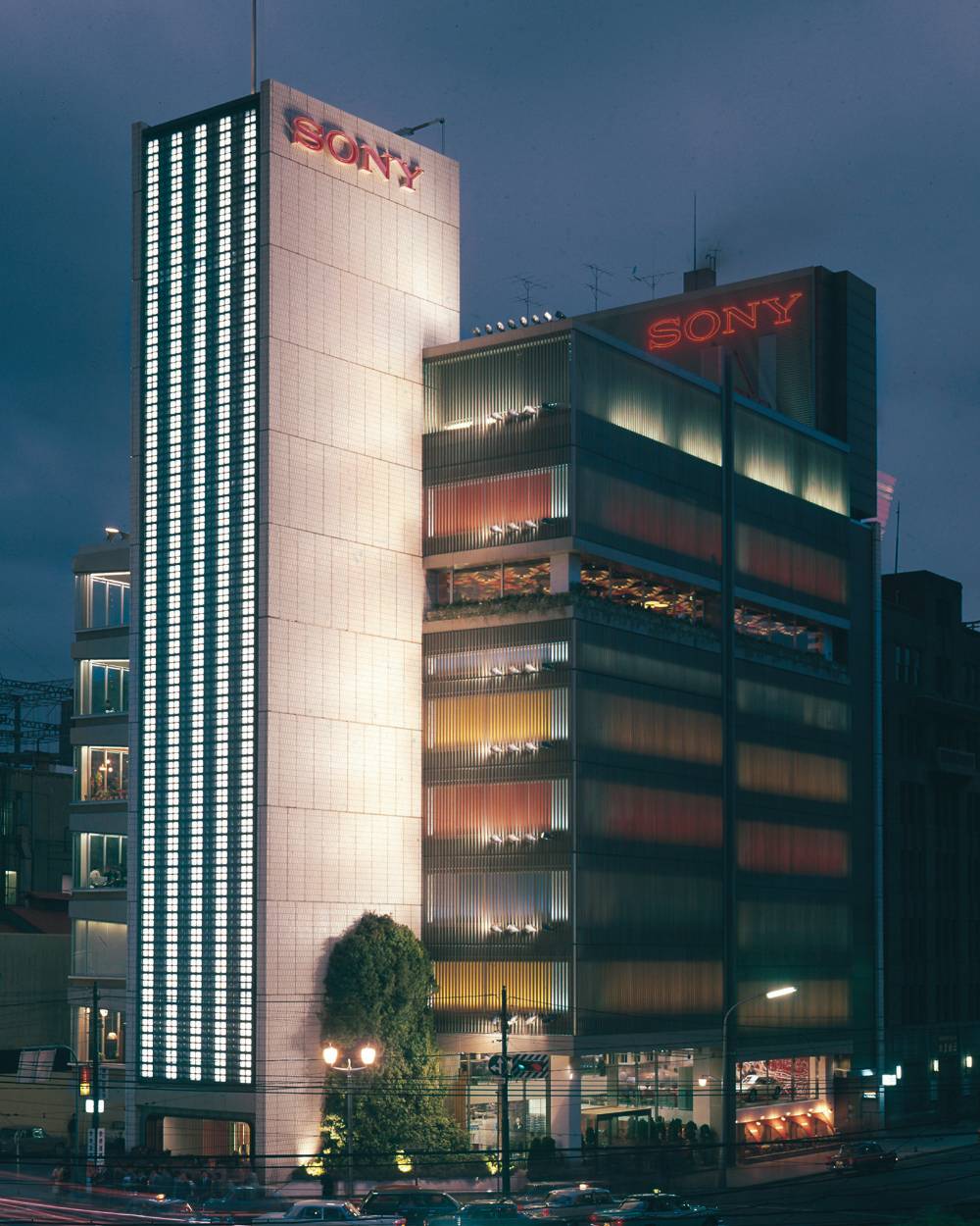 ソニービル外観。夜の数寄屋橋交差点越しのソニービル全景。交差点に面する手前のソニースクエア(屋外イベントスペース)には高さ3階分ほどの馬酔木の生木が植えられている。