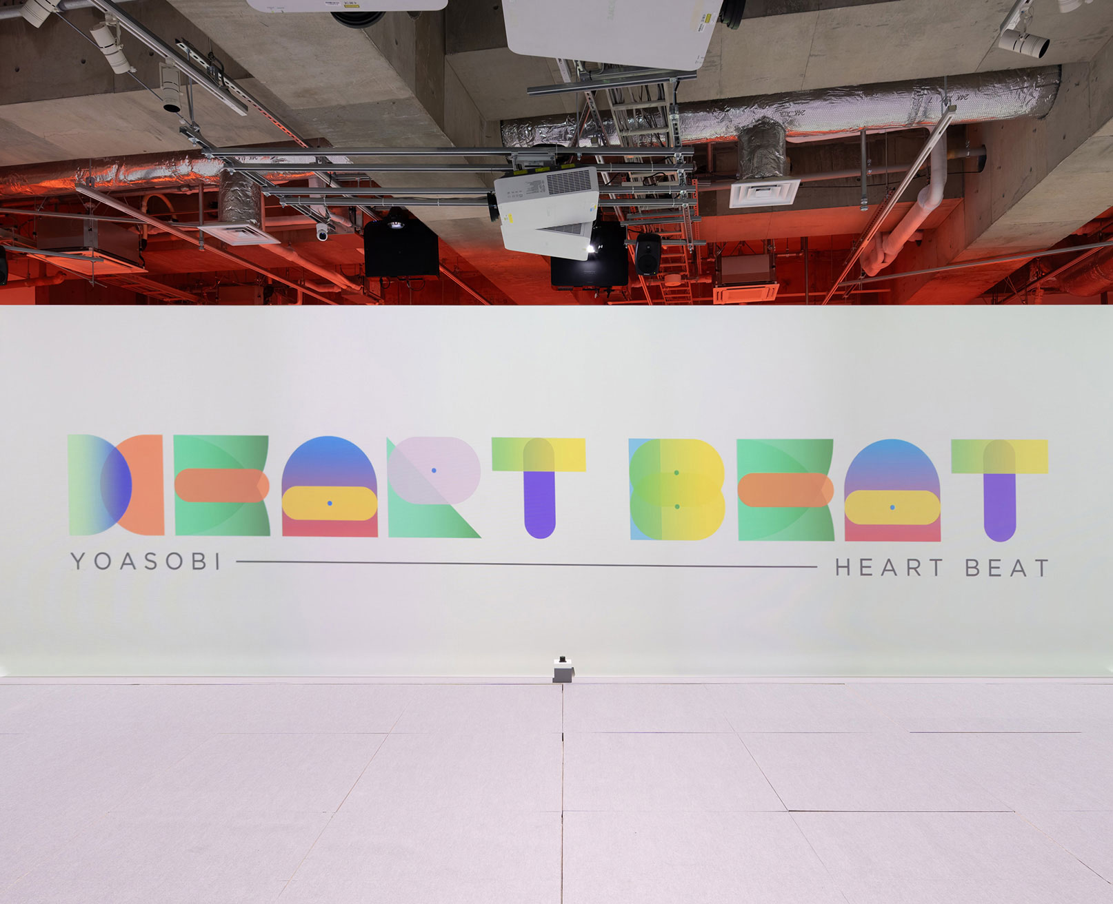 展示風景。“YOASOBI HEART BEAT” が描かれた明るい壁。