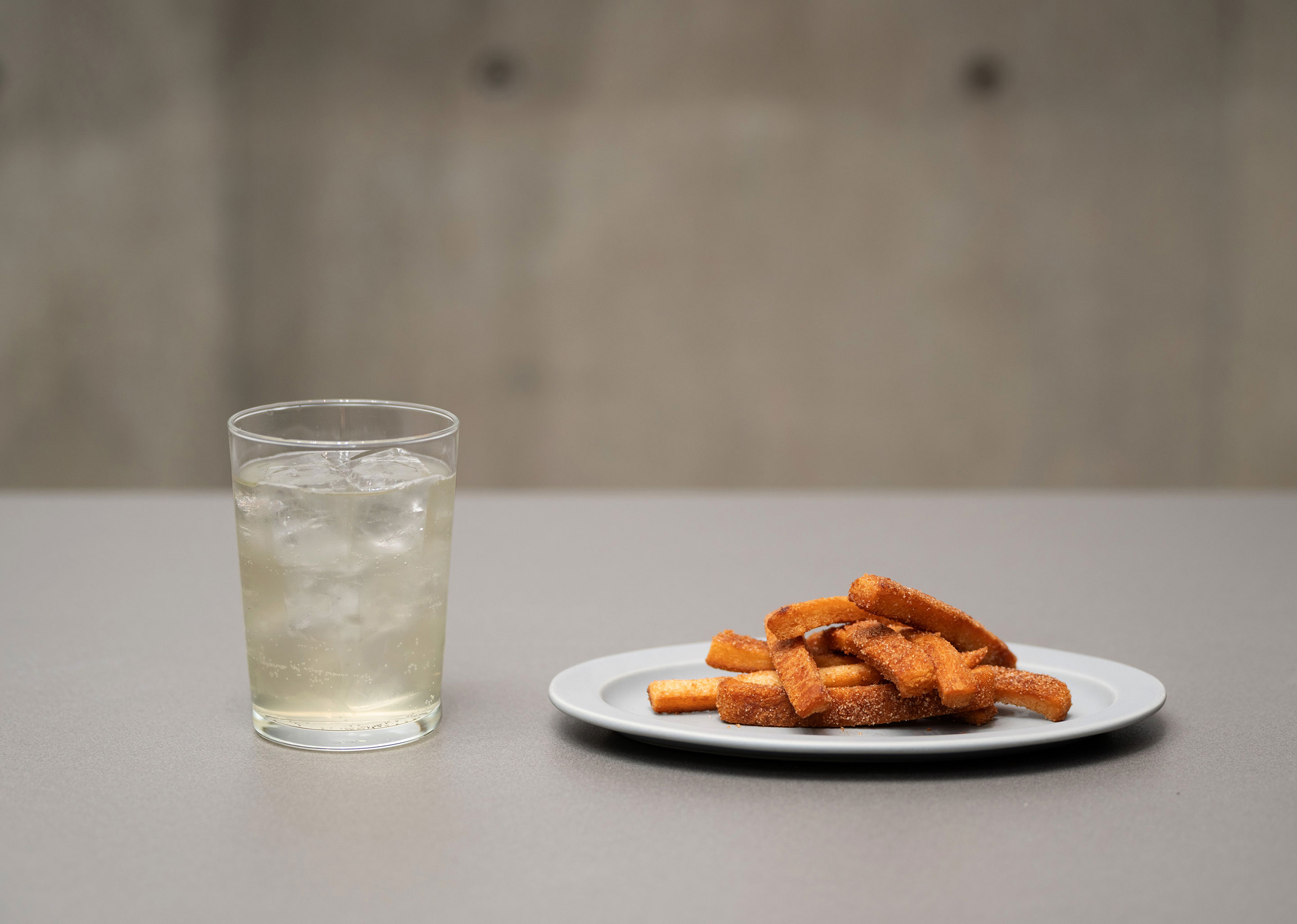 グラスに入ったドリンクと皿にのった揚げたパンの耳の写真。