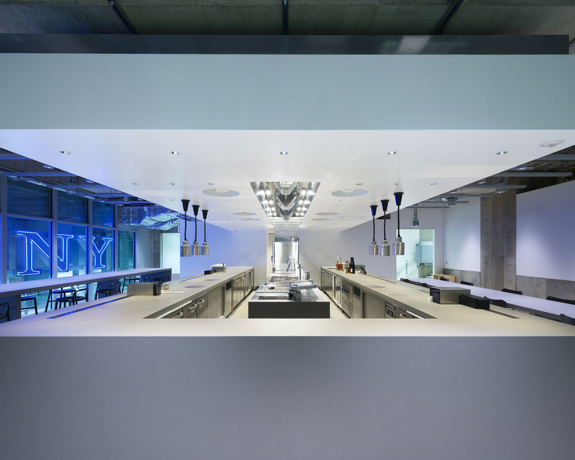 レストランの内観写真。中央に厨房、左にハイテーブル席、右にローテーブル席が見える。