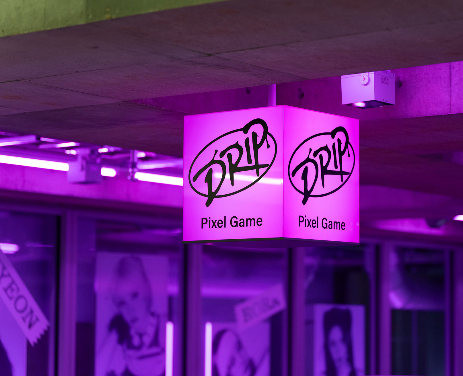 展示風景。ネオンサインに照らされた空間に吊るされた、ピンク色に光る「DRIP Pixel Game」の立体看板。