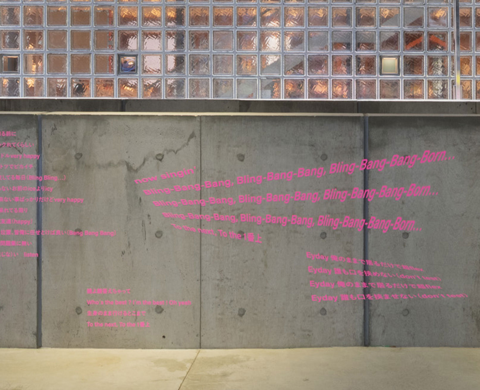 展示風景。コンクリート壁にピンク色の文字で歌詞が描かれている。