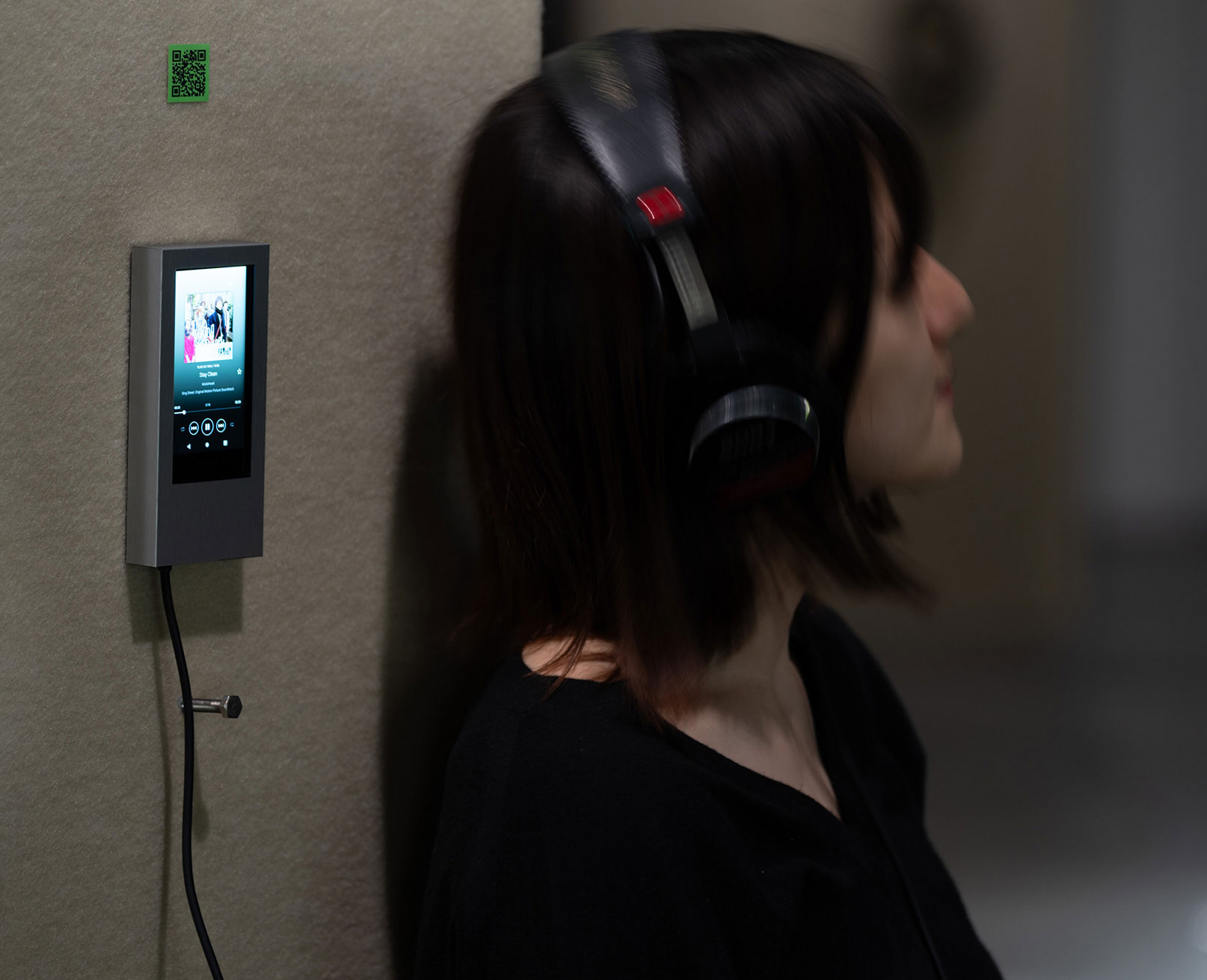 展示風景。来場者がヘッドフォンを装着し、柱に設置されたデバイスから音楽を聴いている様子。