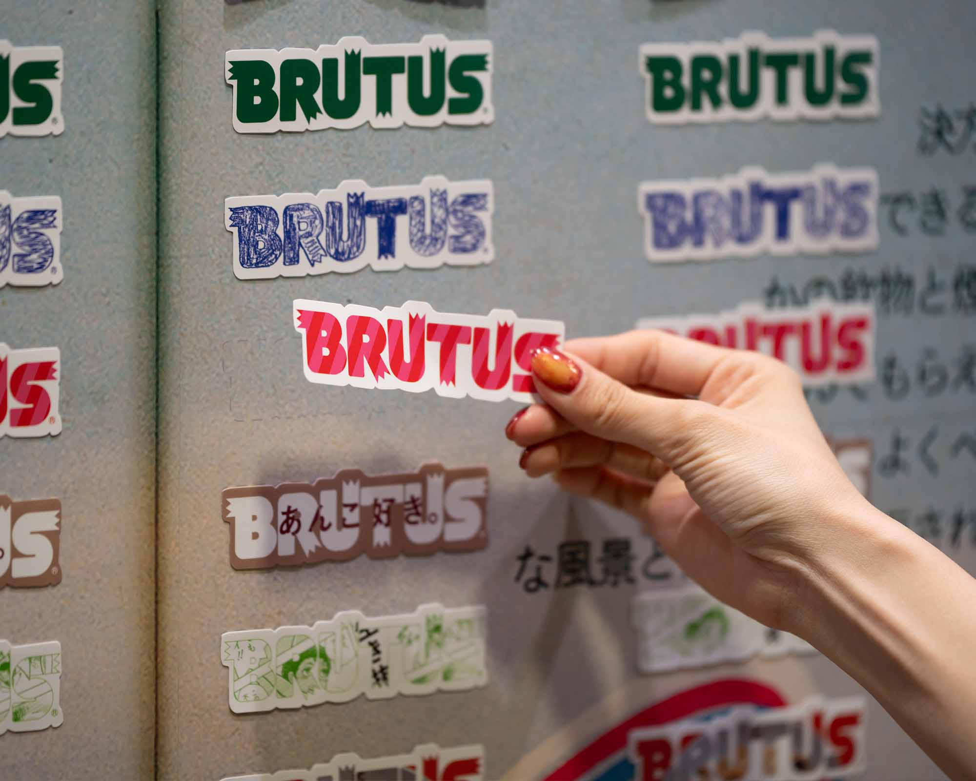 B2 展示風景 「マガジンハウスのA to Z」で BRUTUSのステッカーを手に取ったロゴの写真。