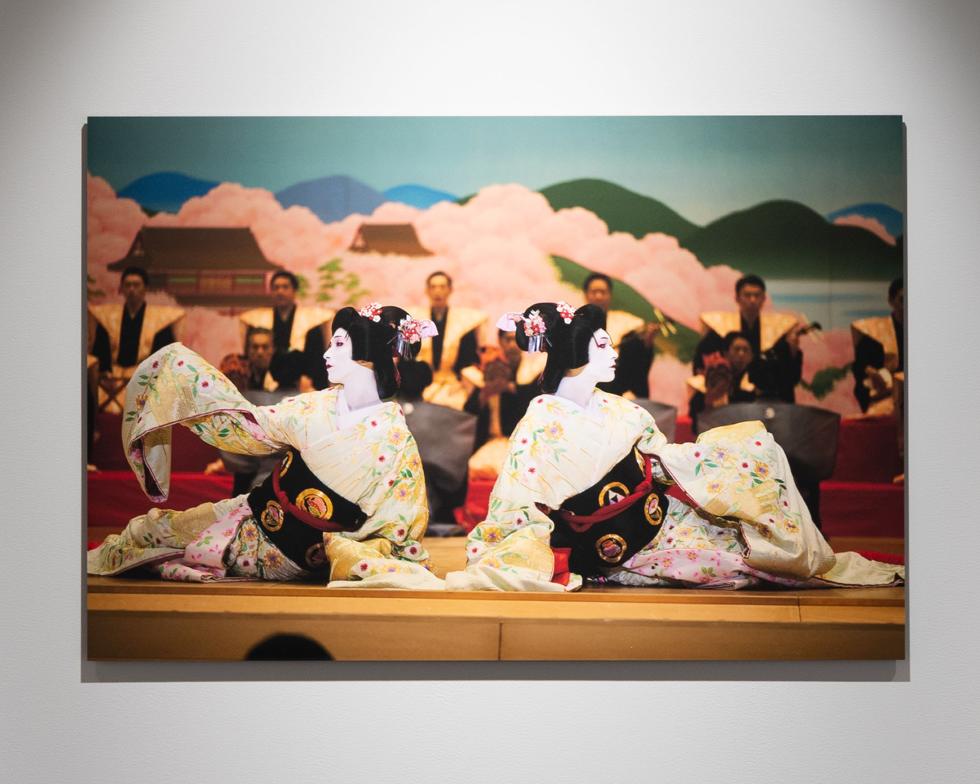 映画「国宝」のシーンの一部。舞台上の場面を捉えた写真作品。人物の動きや衣装の色彩が印象的で、映画や舞台の世界観を伝える展示として壁面に設置されている。