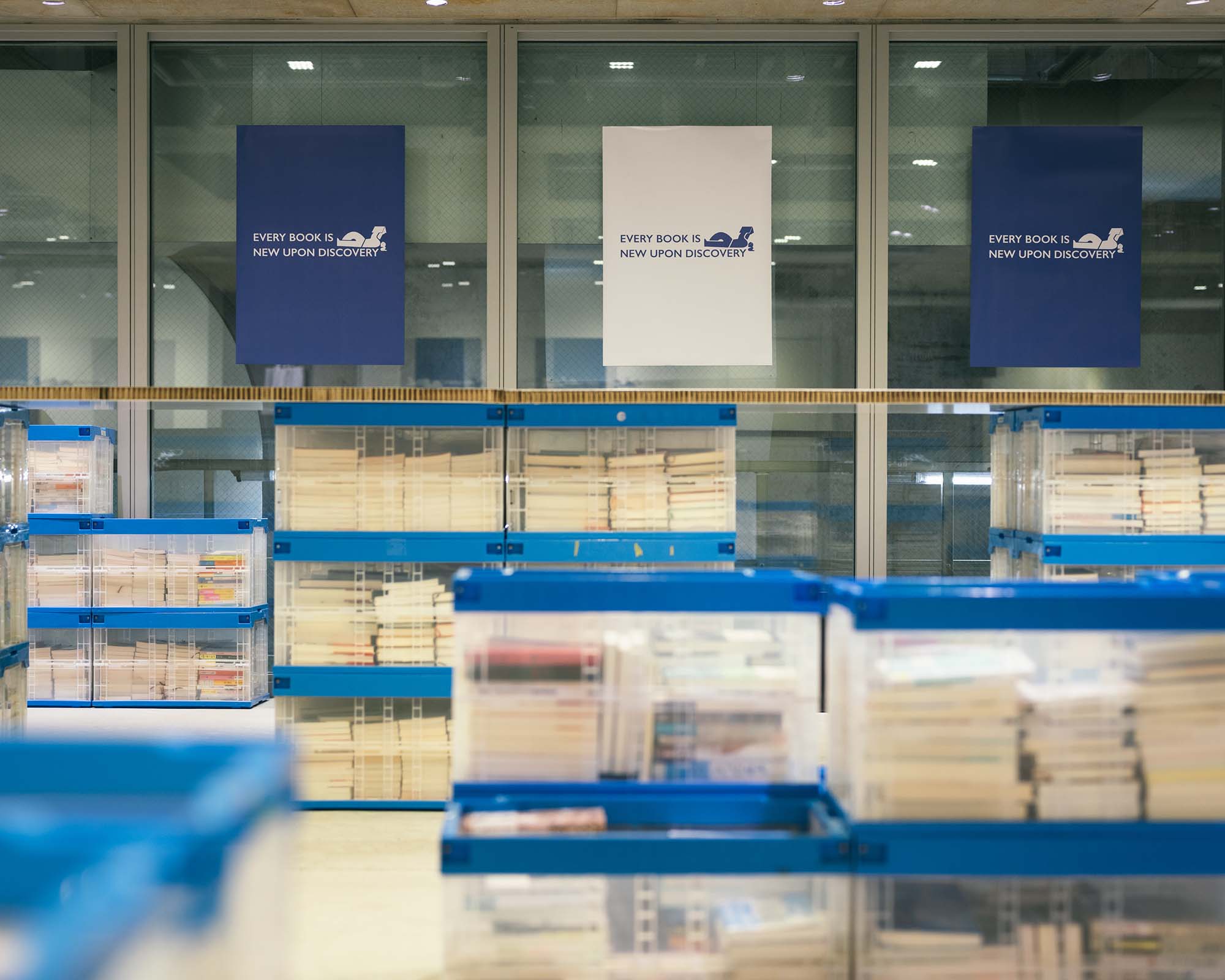 Ginza Sony Parkの窓際に並ぶ本のコンテナ。背後には「EVERY BOOK IS NEW UPON DISCOVERY」のポスターが掲げられている。