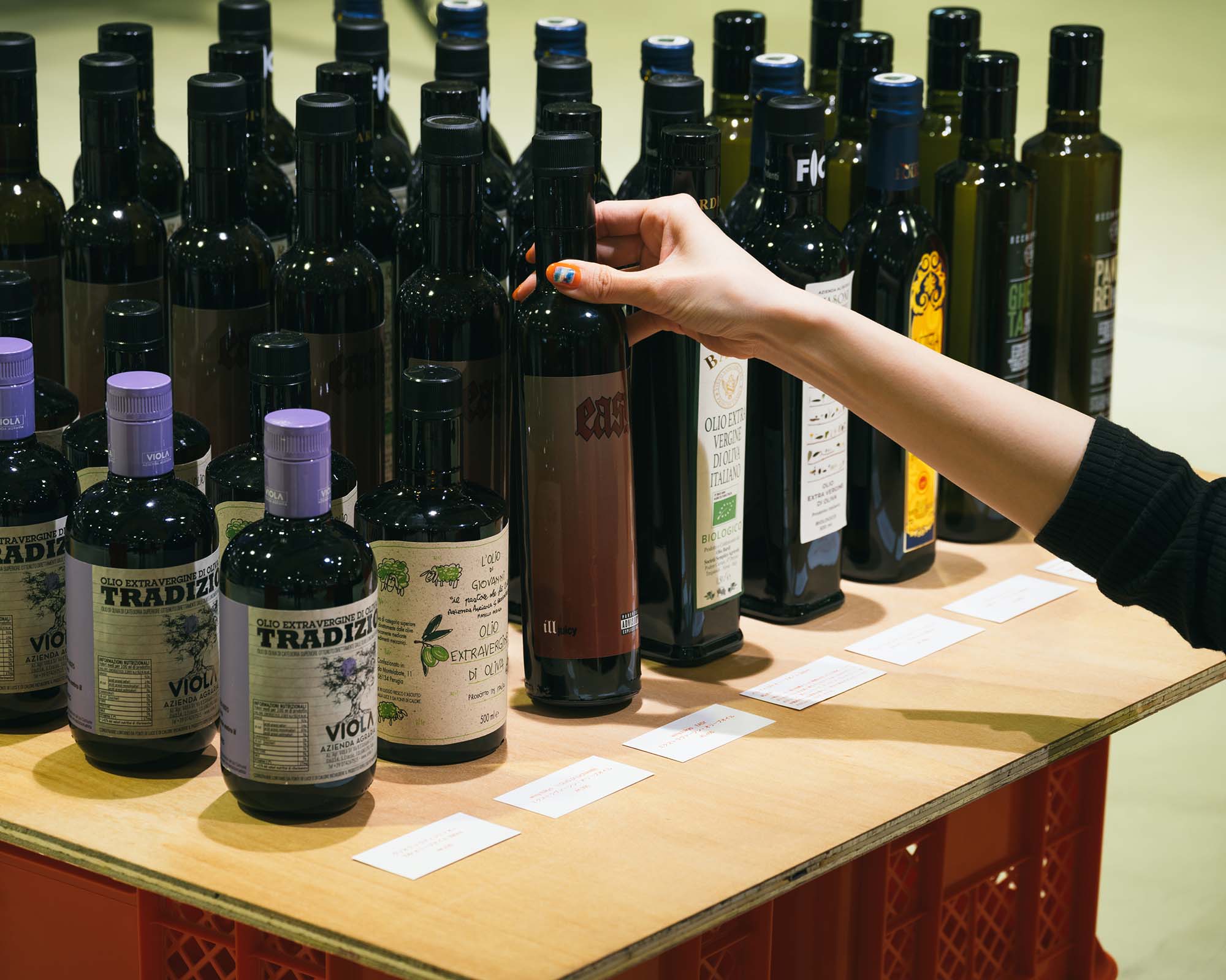 At PASTA PLAZA in Ginza Sony Park, a visitor selects a bottle from a display of olive oils.