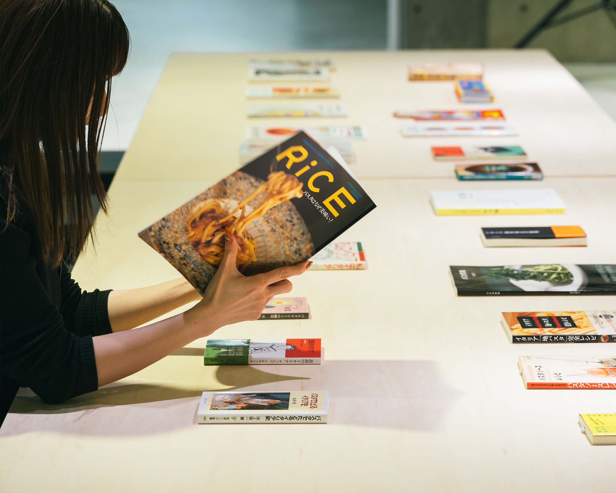 At PASTA PLAZA in Ginza Sony Park, books on pasta and food culture are displayed as a visitor browses through one.