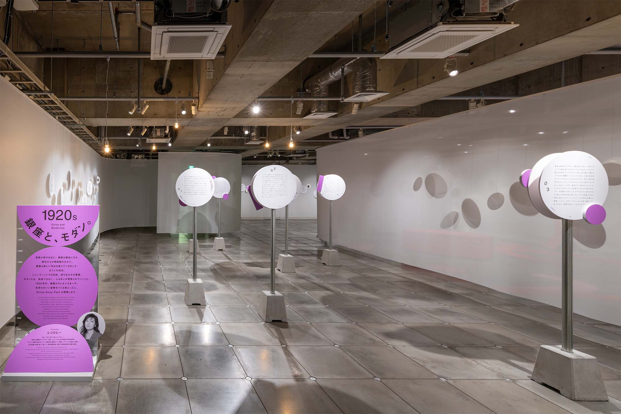 1920s section themed “Ginza and Modernity.” Circular panels line the wall, displaying essay texts about Ginza written by Hiccorohee.
