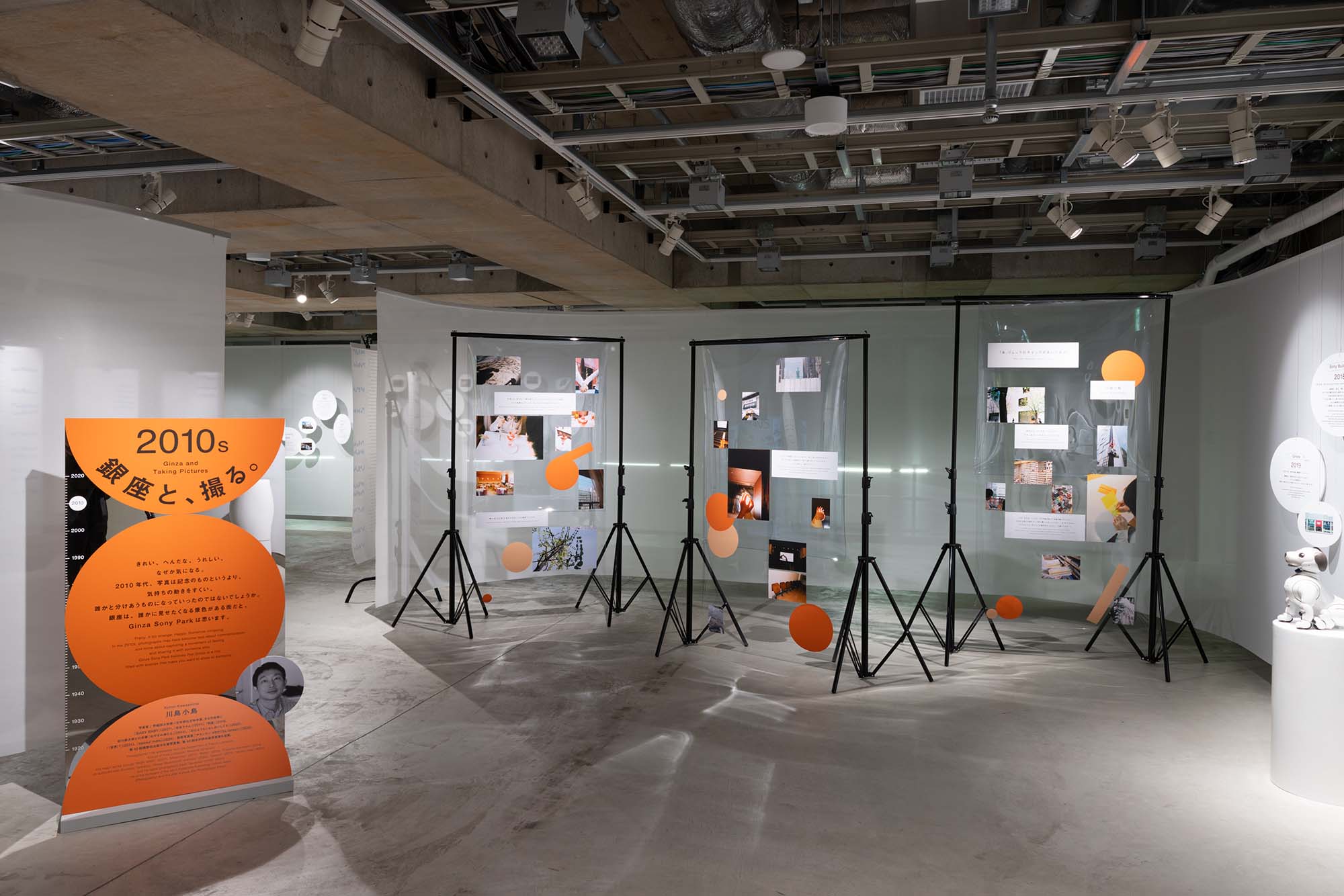 2010s section “Ginza and Shooting.” Transparent panels display photographs alongside essay texts about Ginza written by Kotori Kawashima.