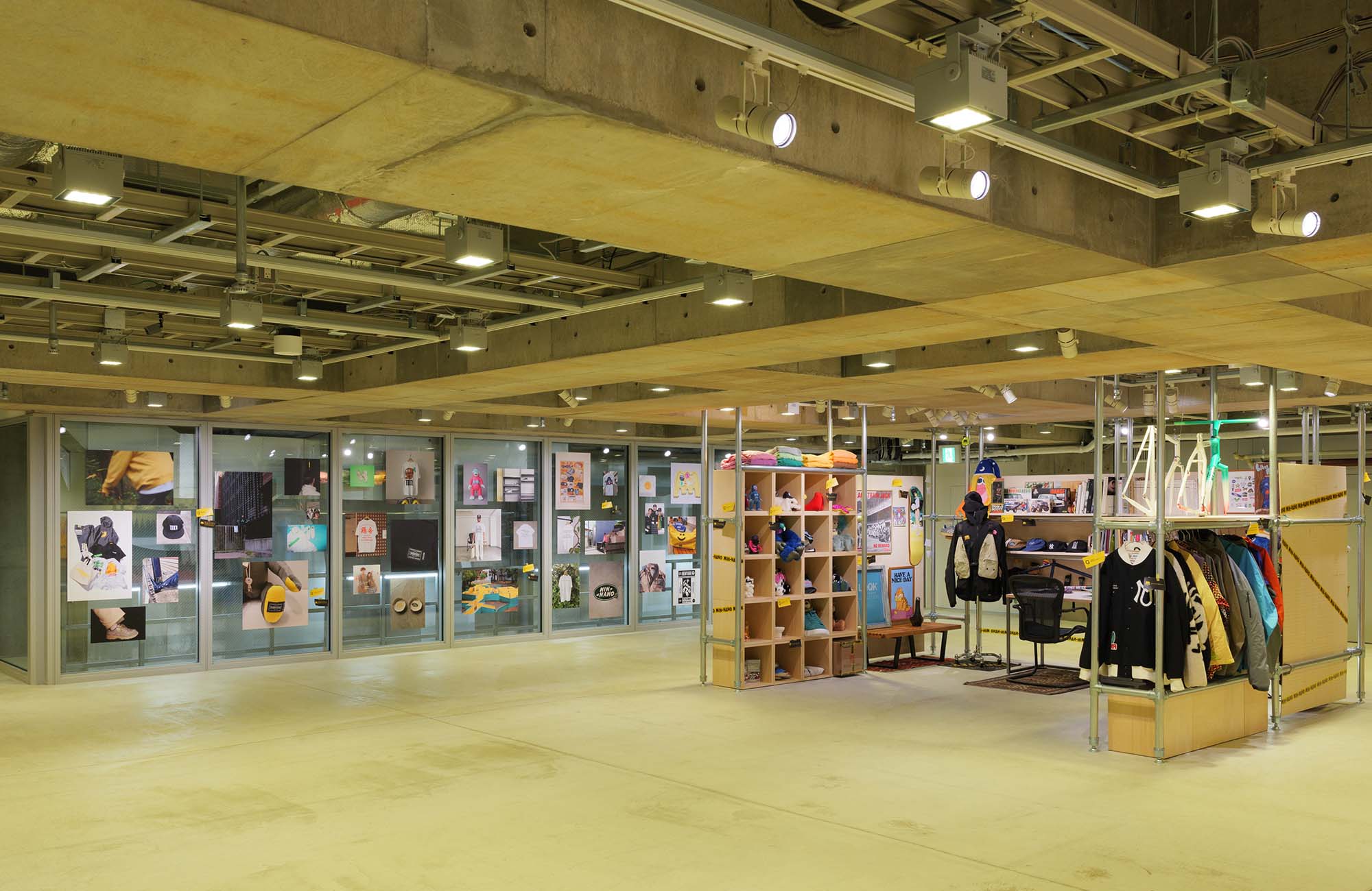 Ginza Sony Park B2の『SHELF PORTRAIT #01 MIN-NANO』の会場全景。コンクリートの空間に、写真が並ぶガラス壁面と、パイプや木製棚などで構成された展示エリアが広がり、ミニマルで開放的な空間デザインが見渡せる。
