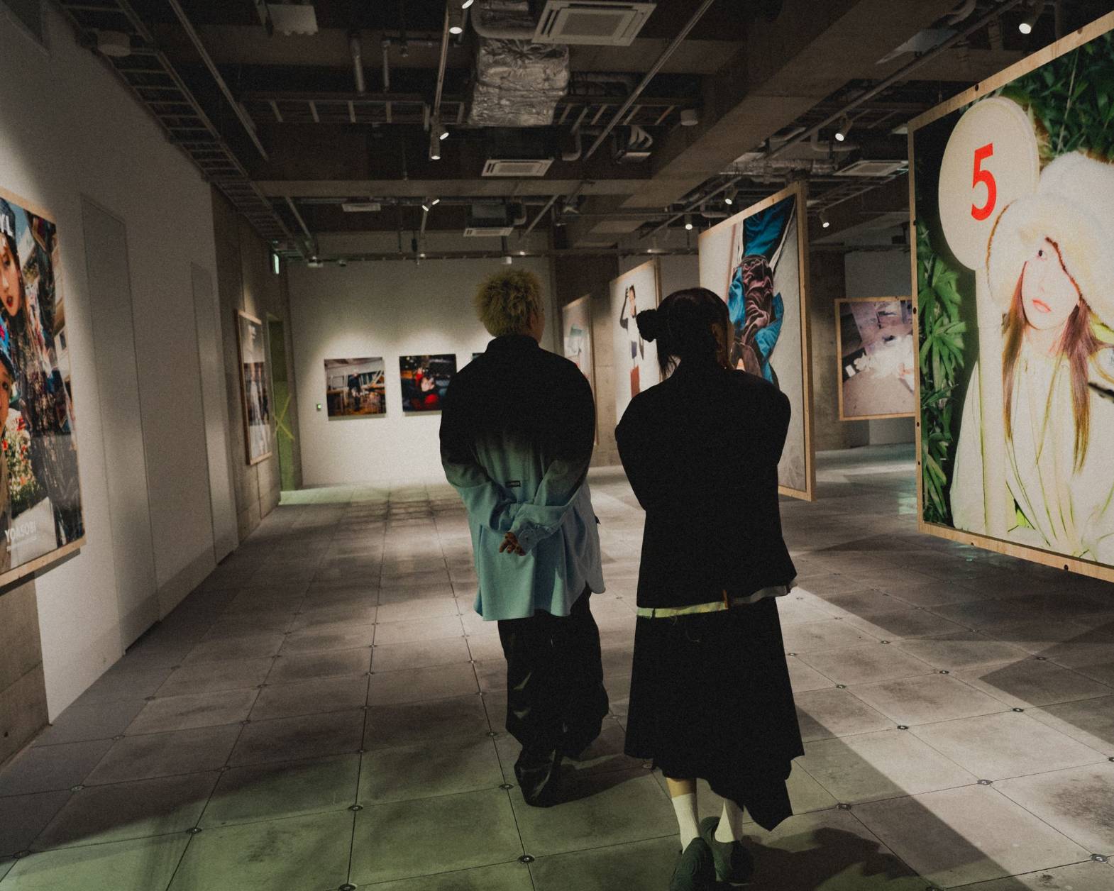 体験の様子。撮りおろしショットが広がる会場を内覧するYOASOBIの二人。