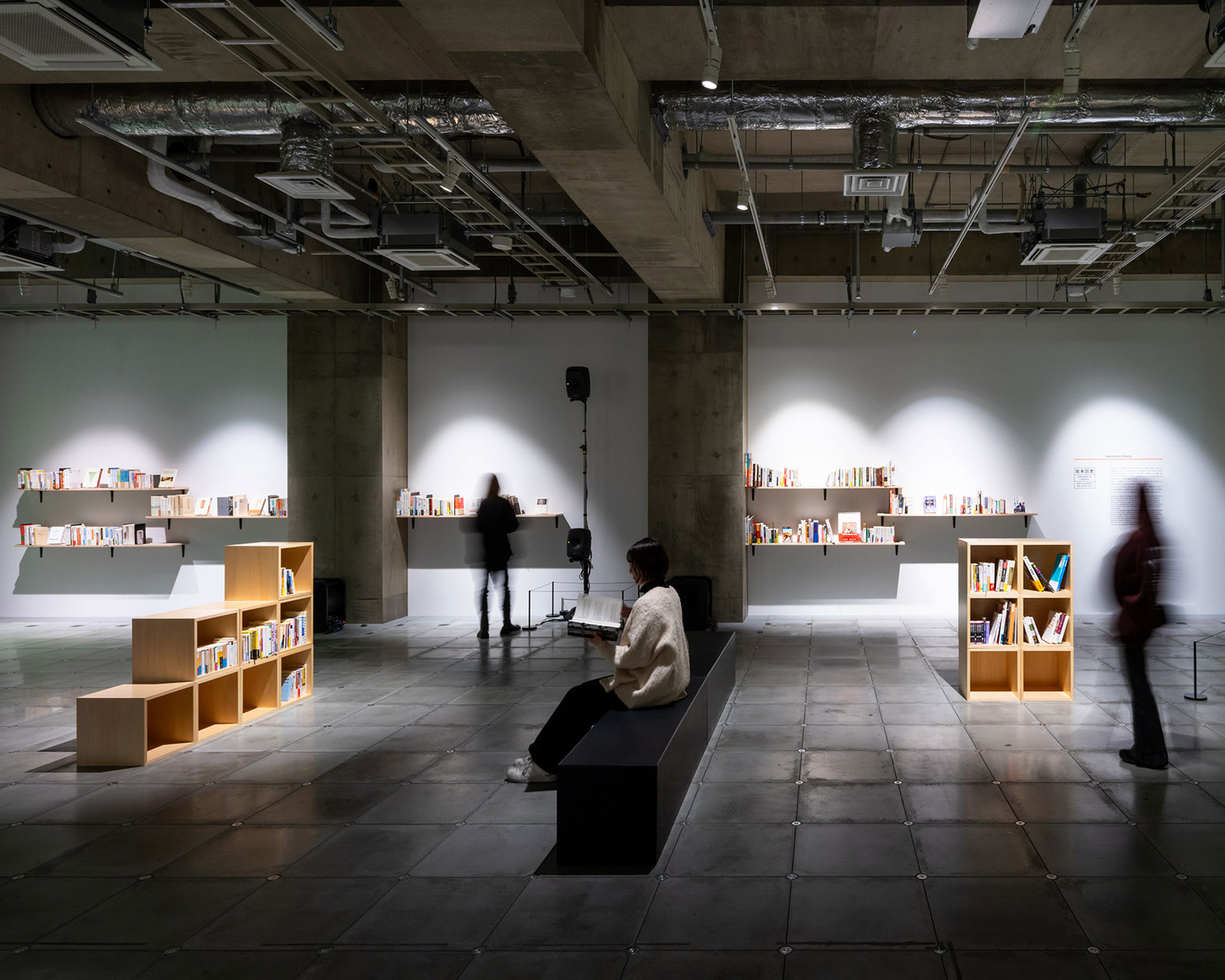 フロアにさまざまな本棚が並び、立ったり座ったりしている人が書籍を読んでいる様子。