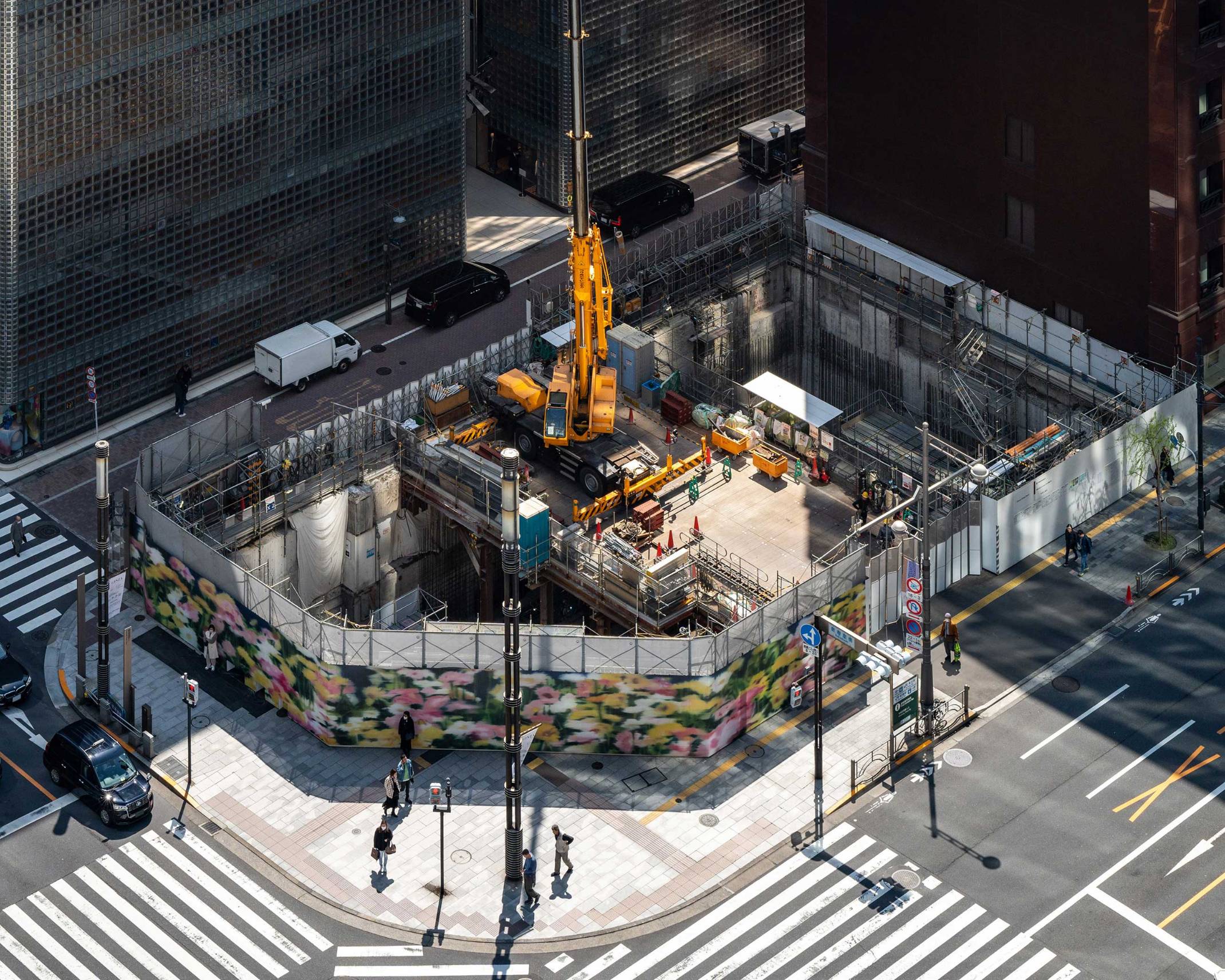 俯瞰風景。仮囲いに覆われたGinza Sony Parkの、地下工事で空いた深い穴の中央に設置された構台にはクレーン重機が載っている。