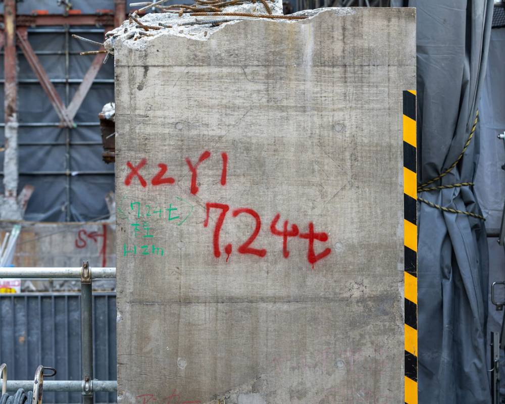 クローズアップ。解体で切り出された旧躯体の梁。赤いスプレーで7.24トンと記されている。