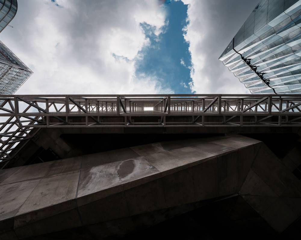 外観。地上から仰ぎみたグリッド状のファサード越しに雲がかかった空が広がる。