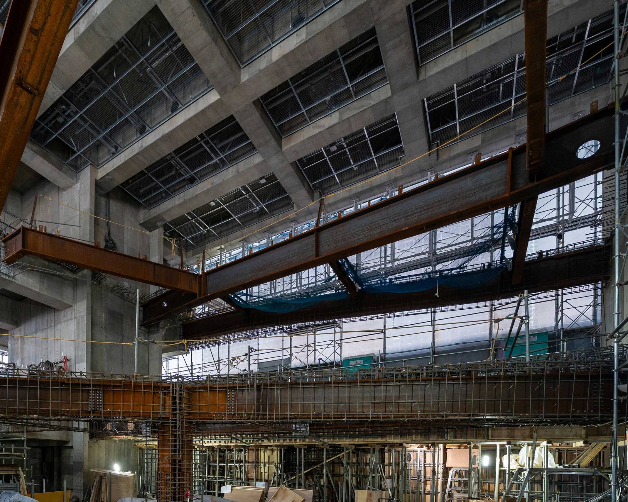 内観。地下1階から天井を仰ぎみた工事中の吹き抜け空間に鉄骨が組まれている。