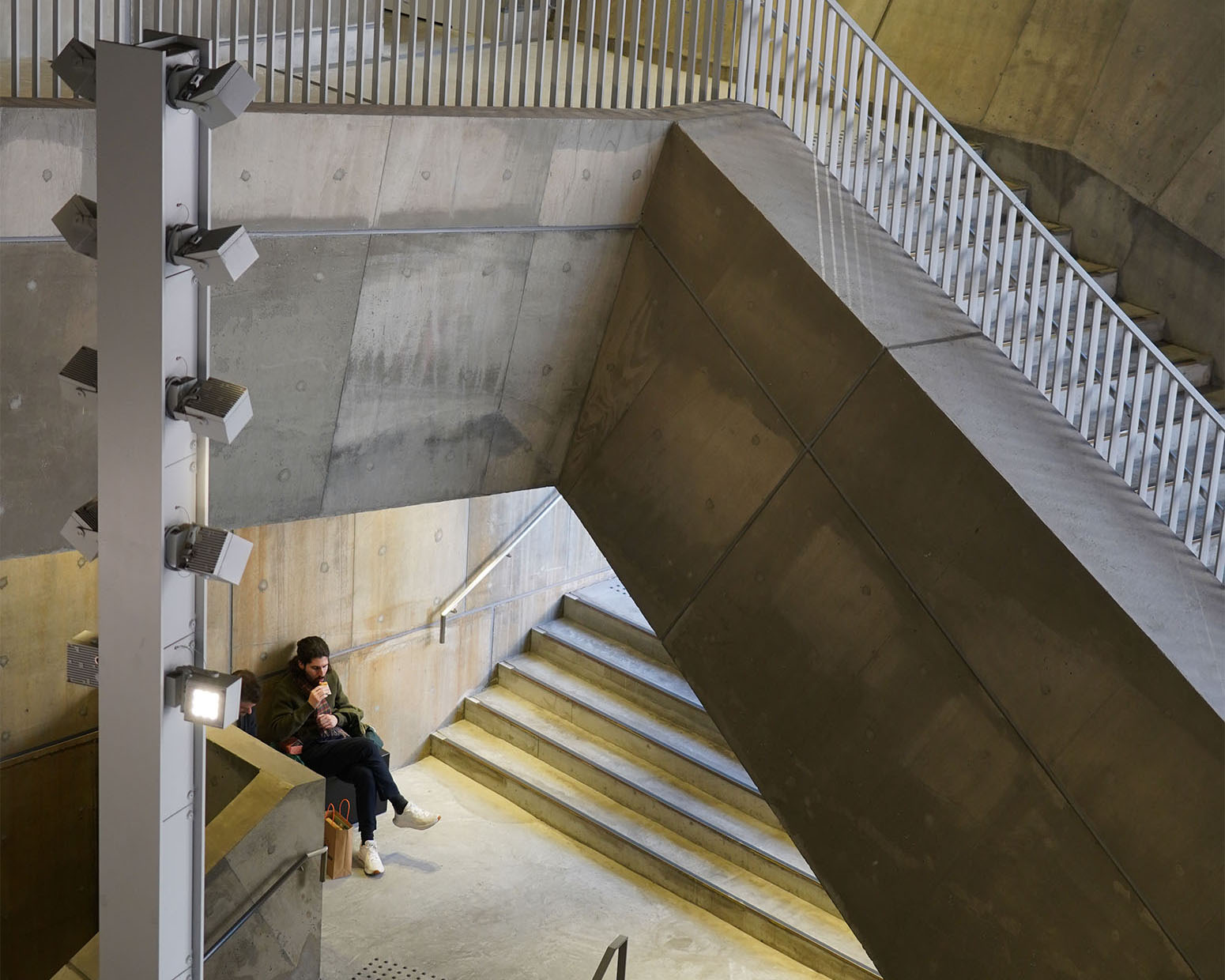 Ginza Sony Parkの立体的な階段空間。コンクリートに囲まれた踊り場で人が腰掛け、静かな時間を過ごす。