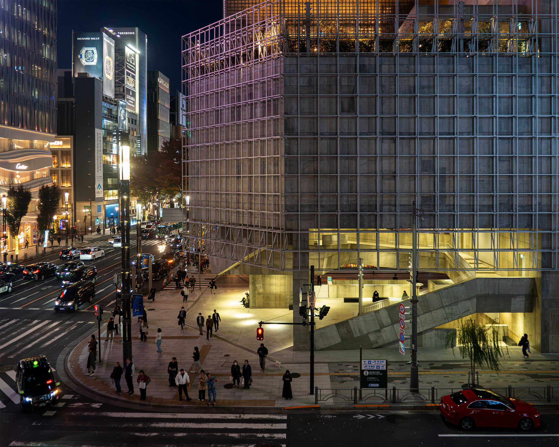 夜のGinza Sony Park外観。格子状のグリッドフレームと明るく開かれた内部が、銀座の交差点に浮かび上がる。