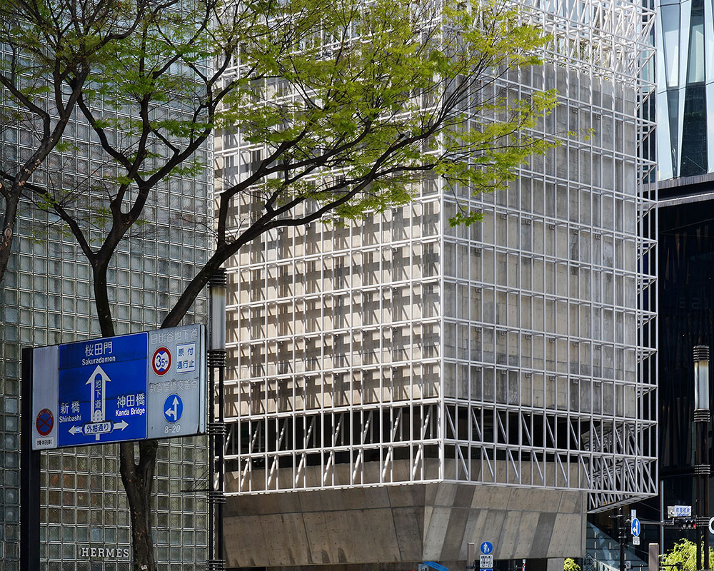 横断歩道を待つ人の奥に見える、新緑の街路樹とGinza Sony Parkの外観。