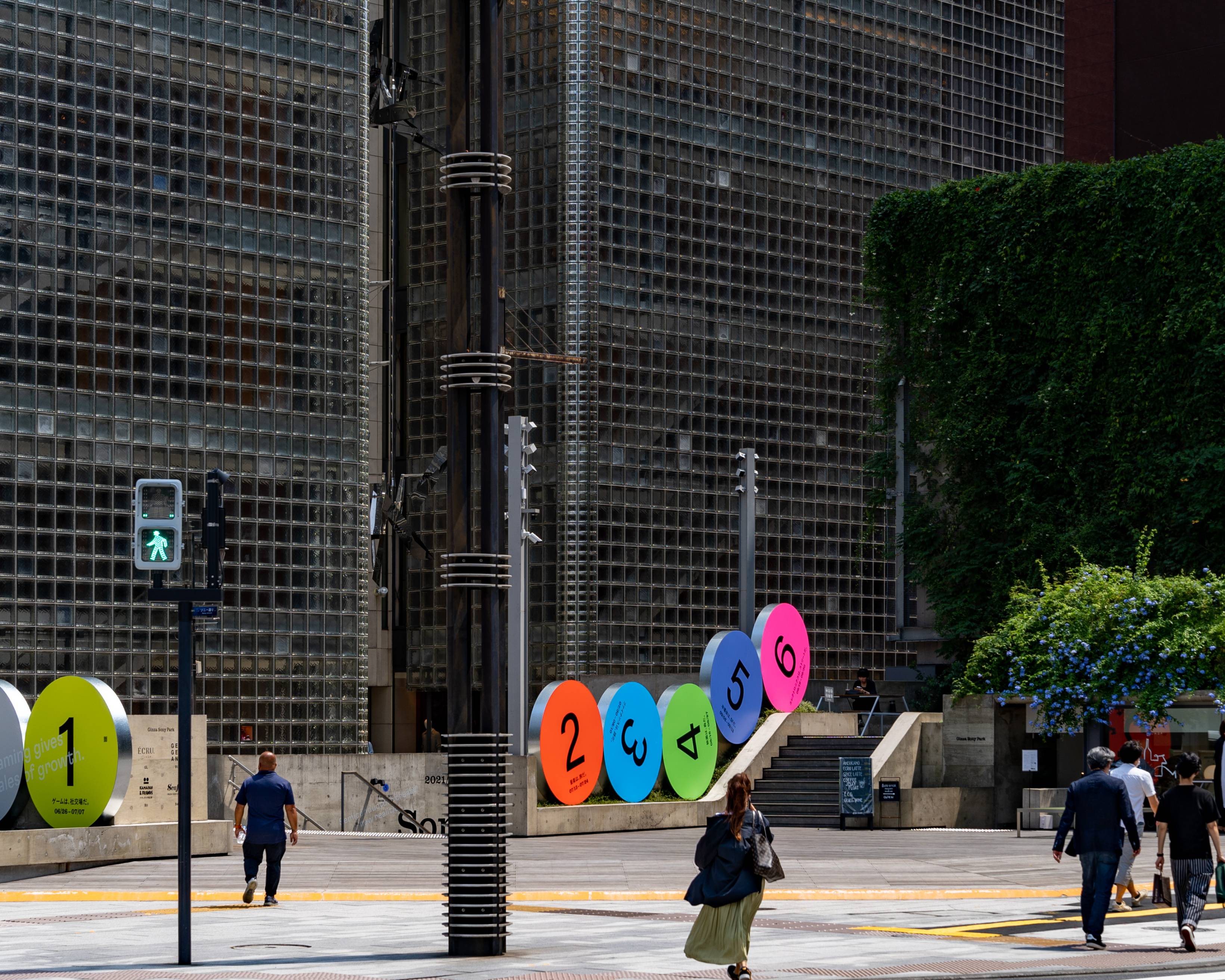 外観。地上階に1から6までの数字それぞれ描かれた6つの丸いオブジェが並んでいる。隣接した歩道を歩く人々がいる。