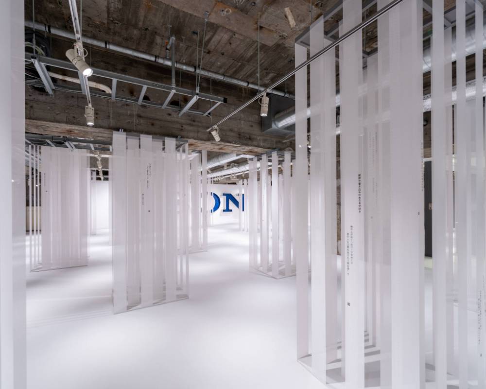 展示の様子。地下空間に森の木々のように天井から吊された何本もの白い布。それぞれの布には映画作品のセリフがプリントされている。