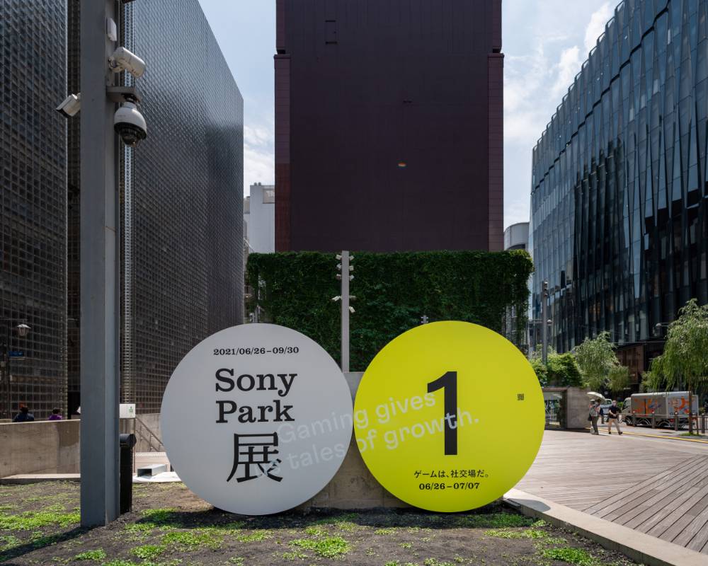 外観。メインビジュアルのグレーの丸いオブジェと「1」と描かれた黄色く丸いオブジェが地上階に並んでいる。