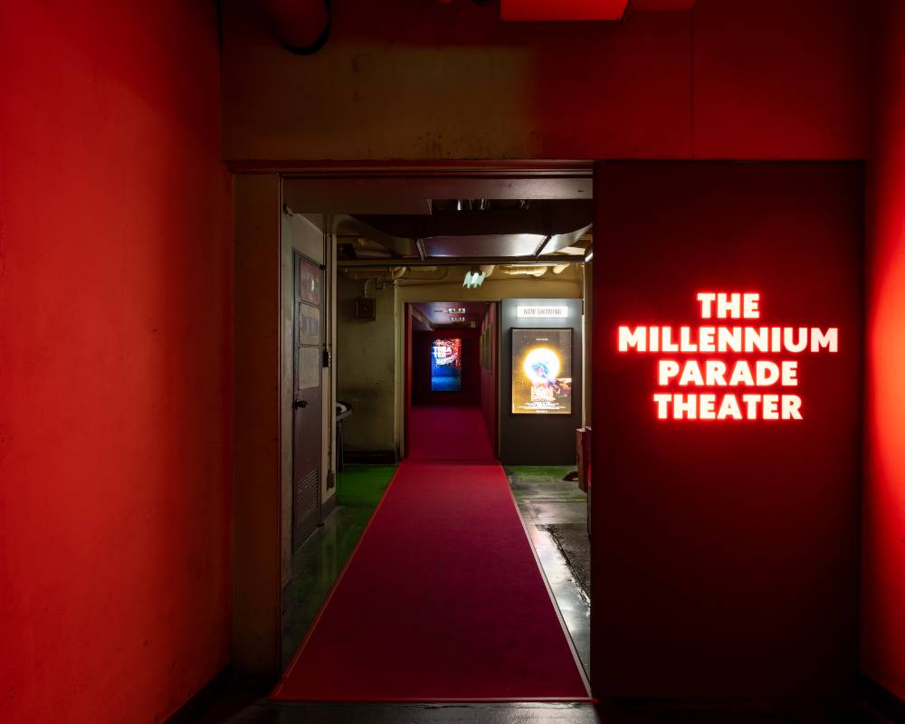 展示の様子。奥にあるシアターに続く通路には赤いカーペットが敷かれ、深紅の壁に囲まれた入口扉には「THE MILLENNIUM PARADE THEATER」のLEDが赤く輝く。