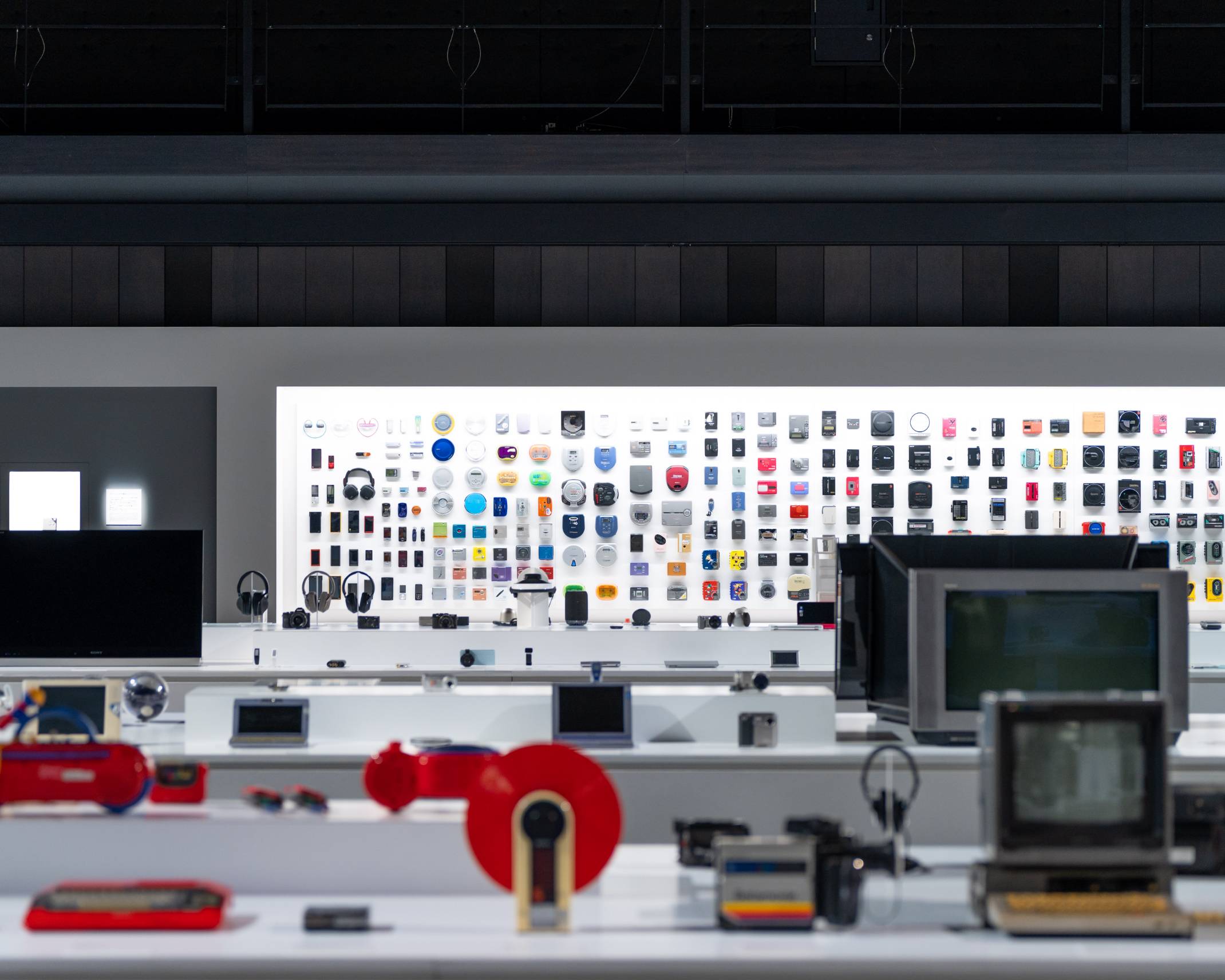 展示の様子。何列もの展示台の先にある奥の壁面には歴代のさまざまなウォークマンが展示されている。