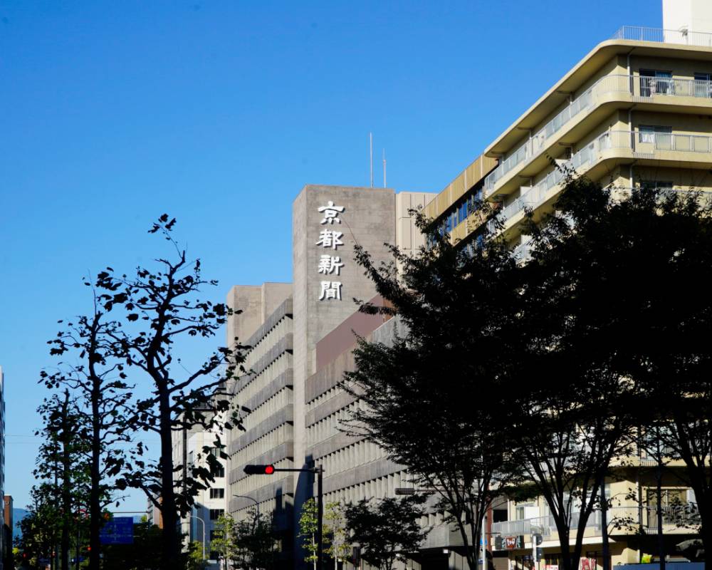 外観。街路樹越しに「京都新聞」という社名が掲げられた建物がある。