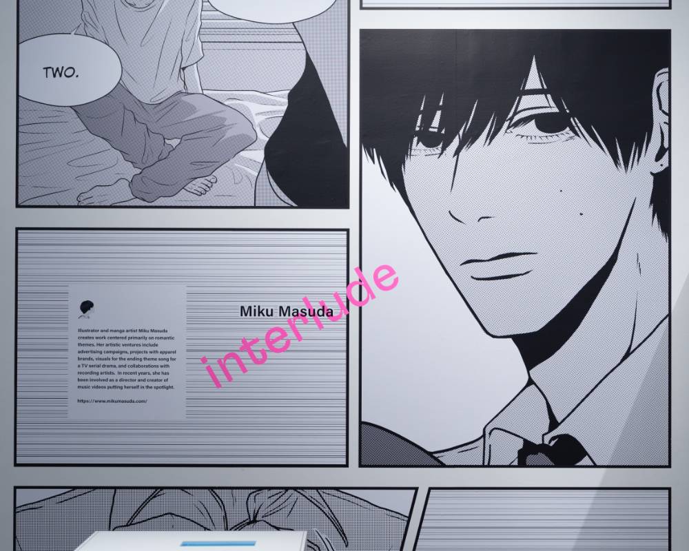 展示の様子。マンガ『Interrude』の男性の顔がアップで描かれているページが壁面に大きく展示されている。