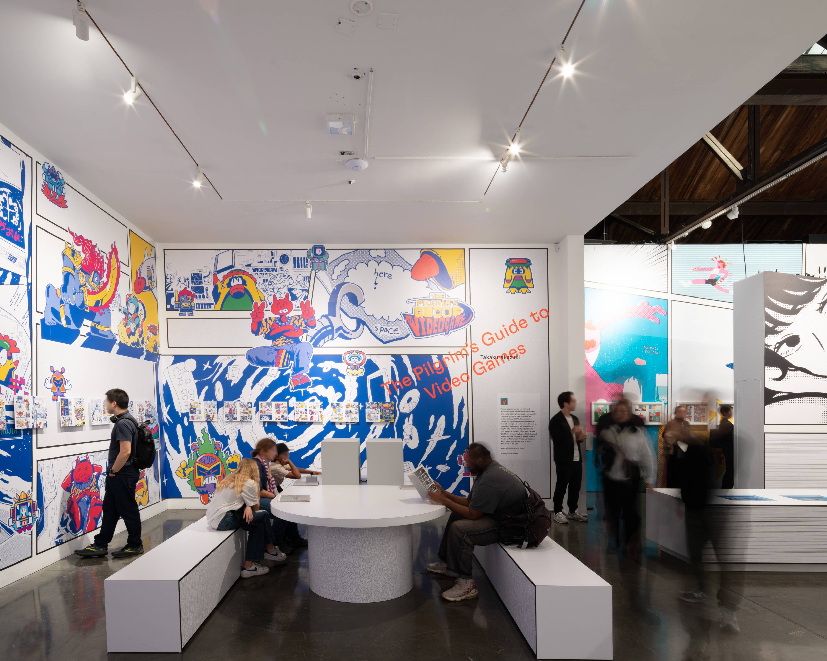 体験の様子。来場者は、壁面の展示、テーブルの上のモニター、本など、さまざまな形でマンガを楽しんでいる。