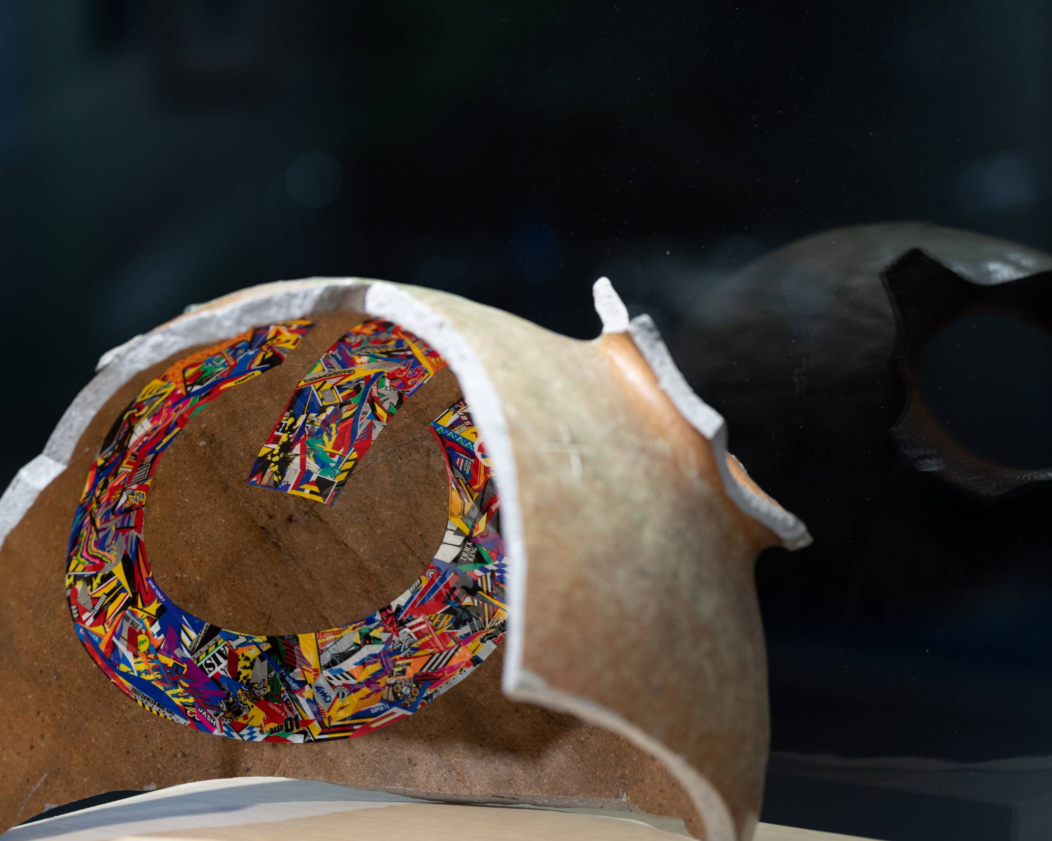 展示品。壺の陶片にステッカーを使用してコラージュした作品が置かれている。