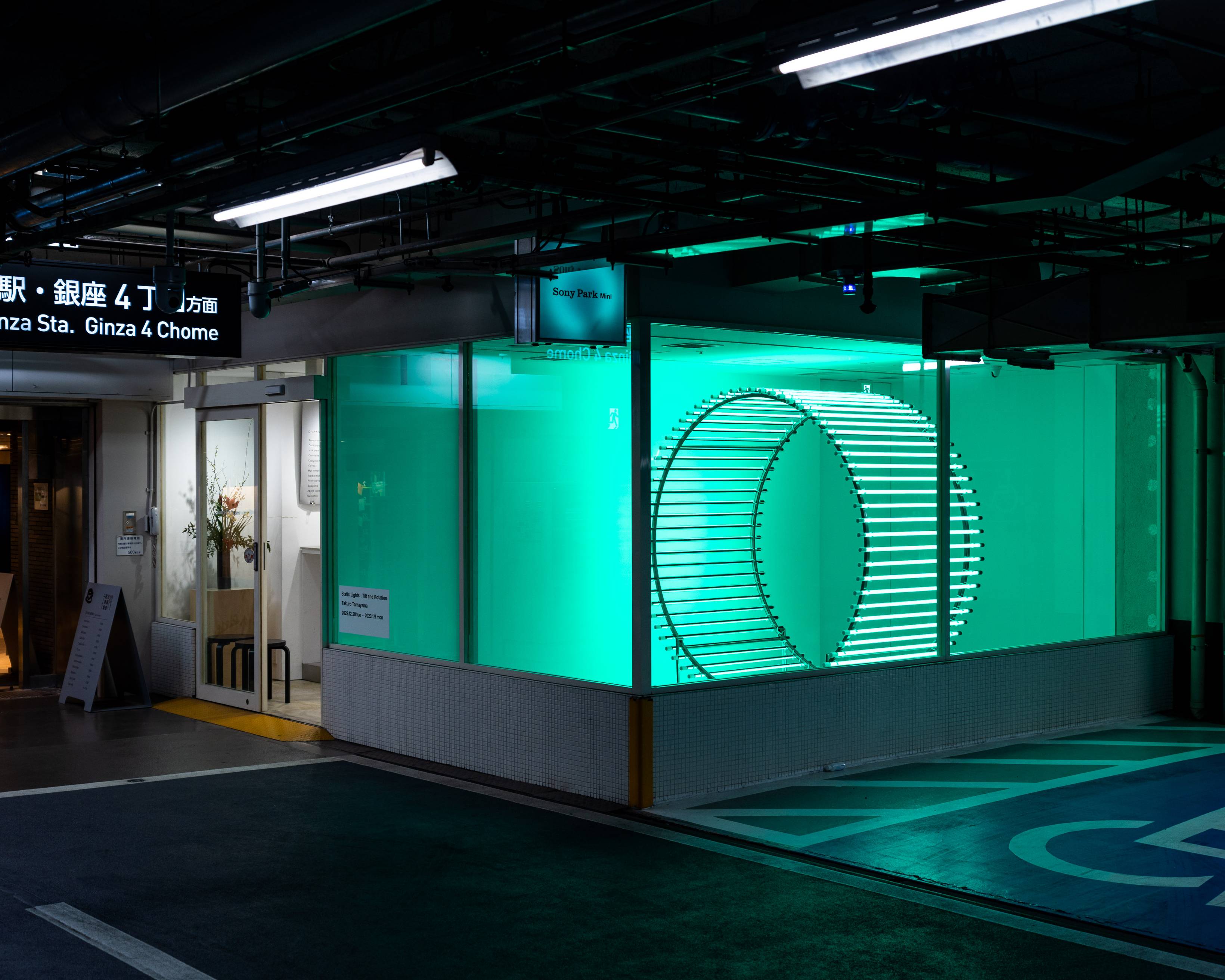 外観。展示スペースに緑色の光を纏う円柱型のオブジェが置かれている。