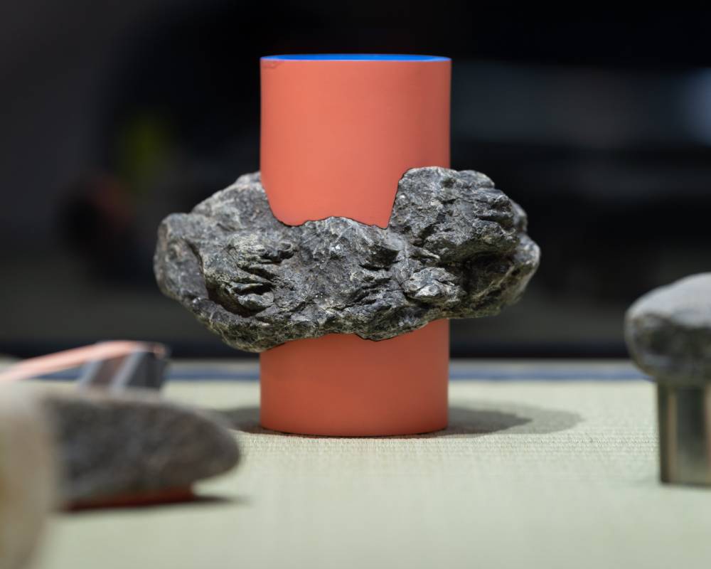 展示品。レンガ色の円柱に石が巻きついたかのようなオブジェが置かれている。