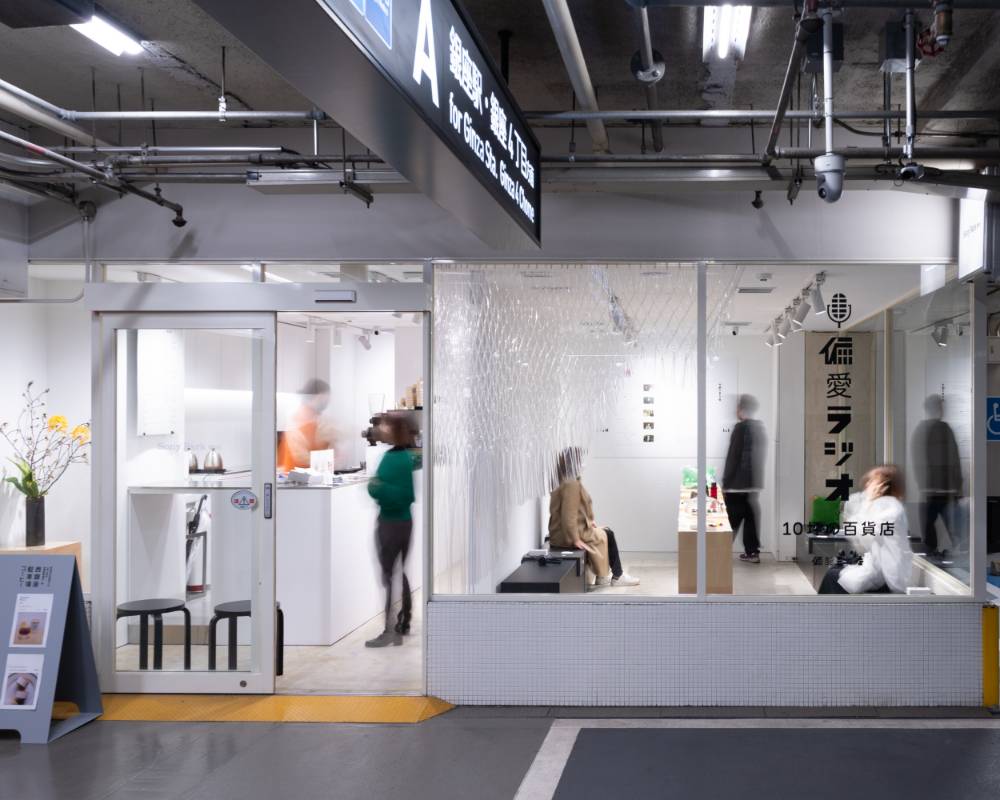 外観。ガラス面はメインビジュアルや透明のカーテンで飾られ、展示スペースは来場者で賑わっている。