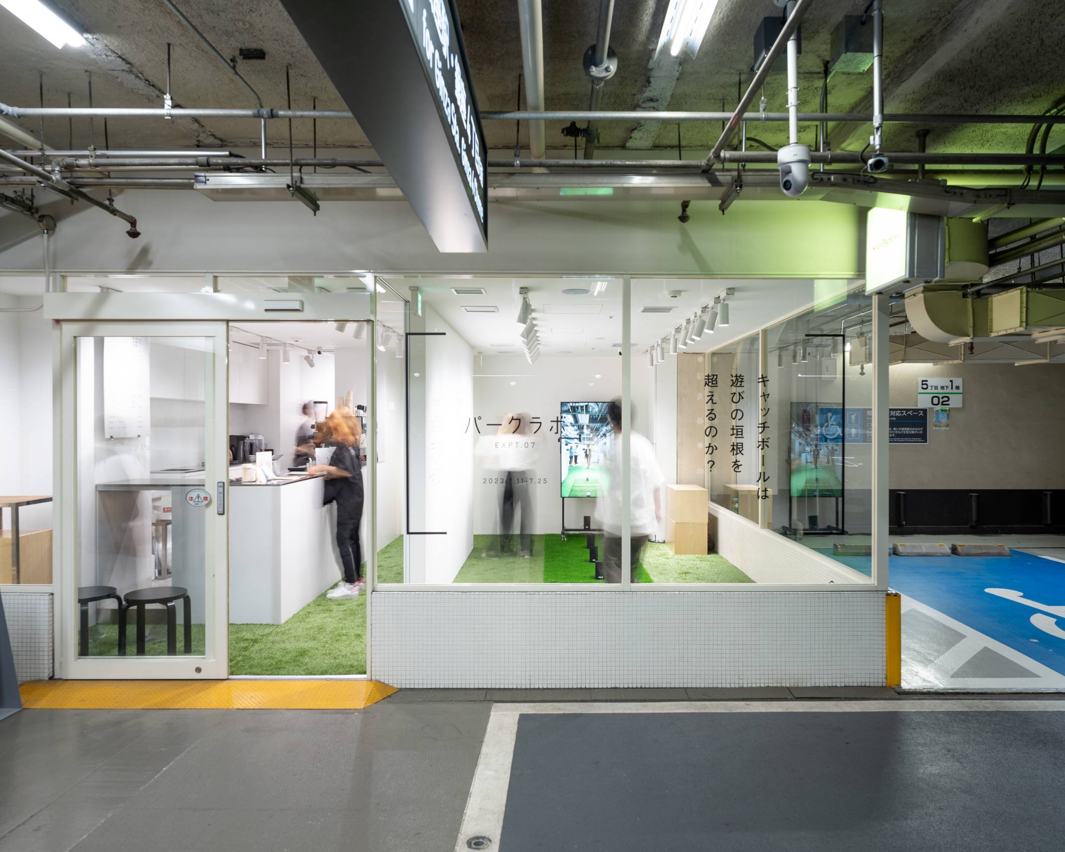 外観。展示スペースの床には緑色の人工芝が敷かれ、奥には縦型のモニターが置かれている。