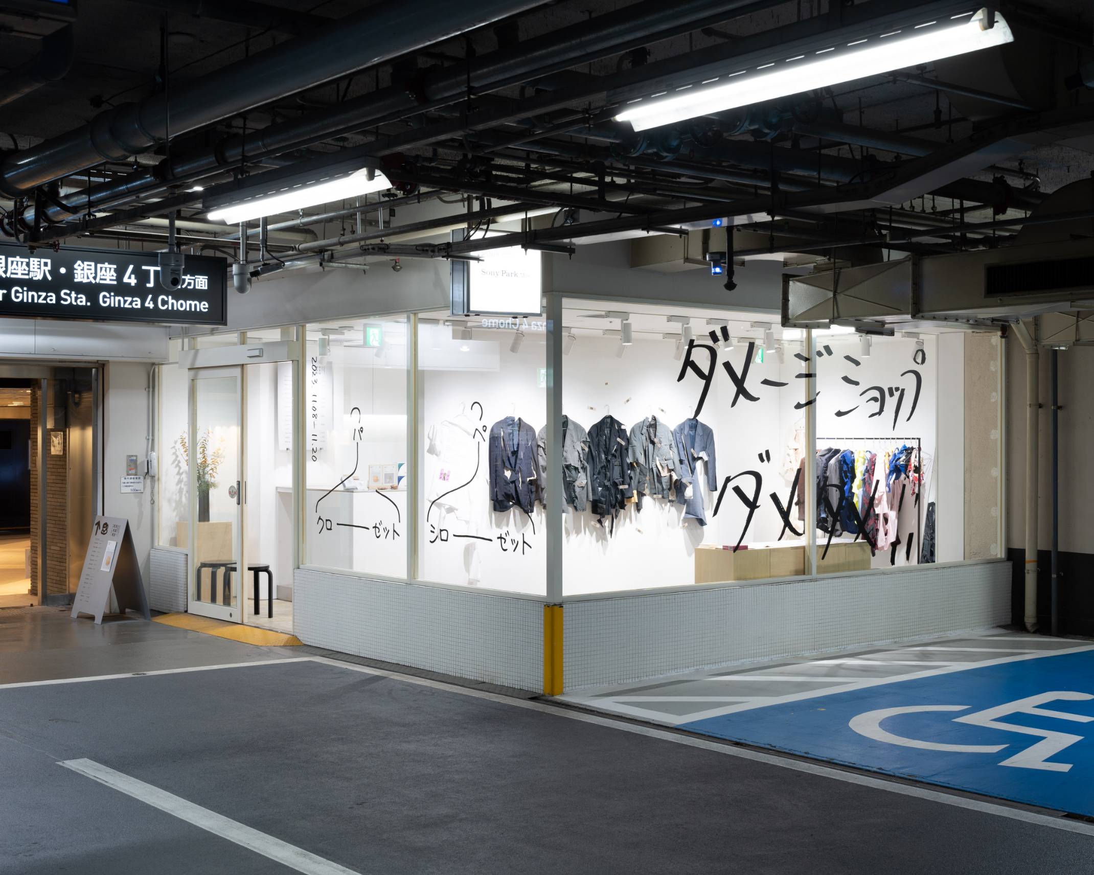 外観。「ダメージショップダメダメ!!」と大きく描かれたガラス面の中のスペースには、さまざまな切れ込みが入った洋服が並んでいる。