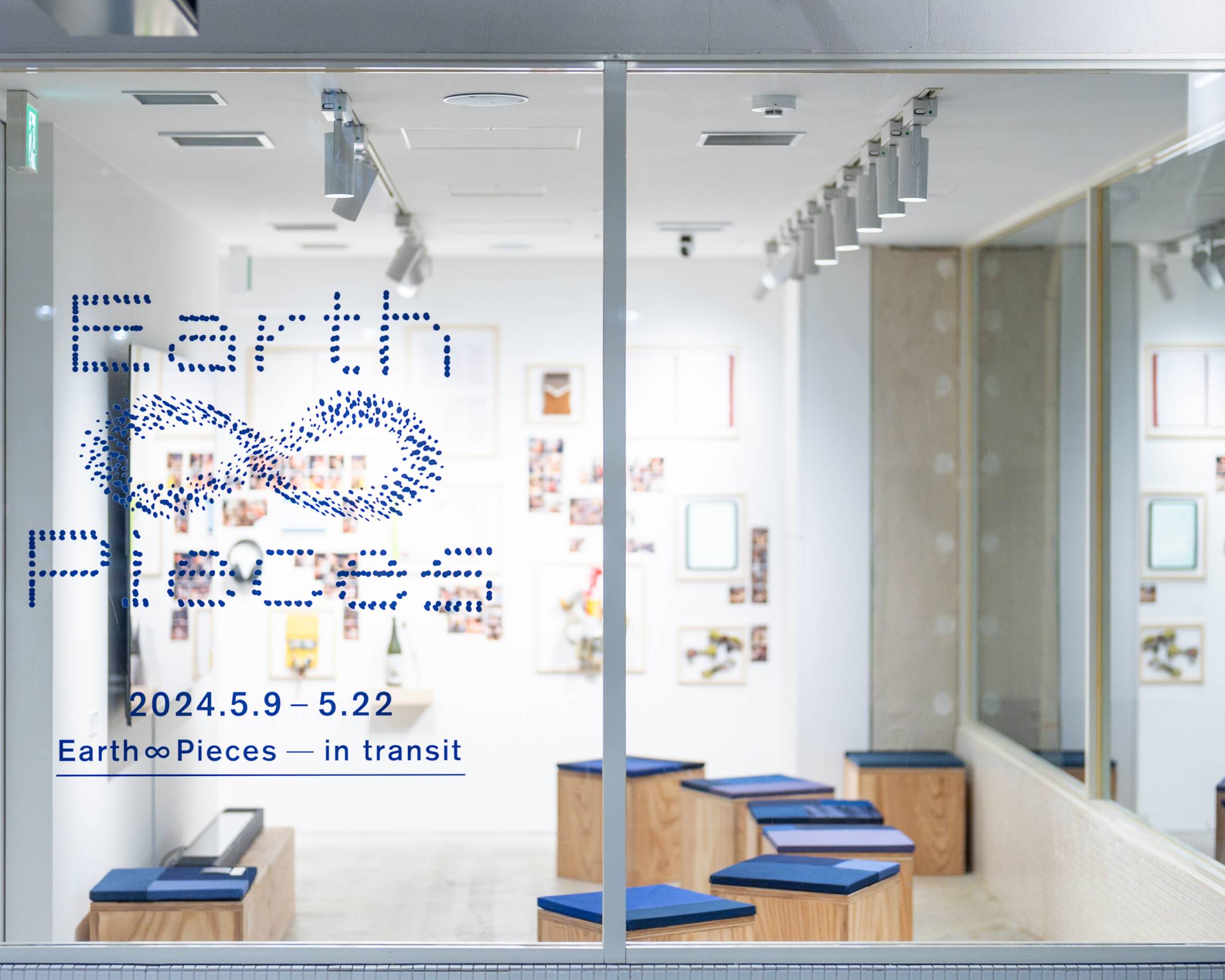 展示の様子。展示スペースには青い座面のスツールが並び、奥の壁面には展示品が並んでいる。