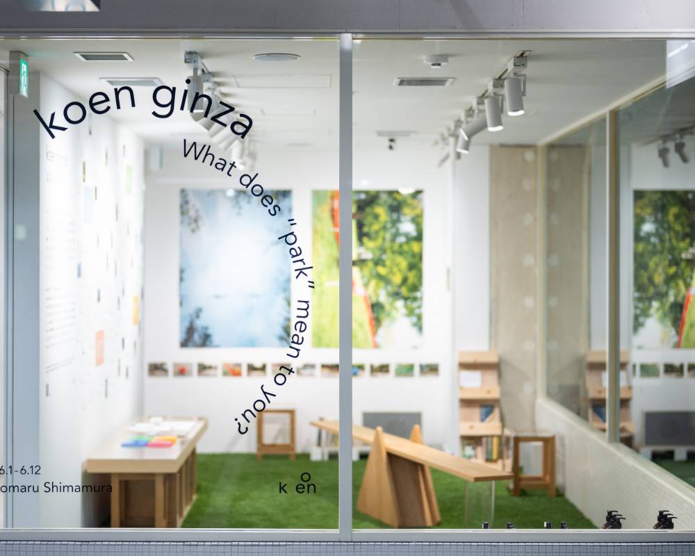 展示の様子。展示スペースの壁面には写真が飾られ、緑の芝が敷かれた床には遊具のような木製の家具が置かれている。