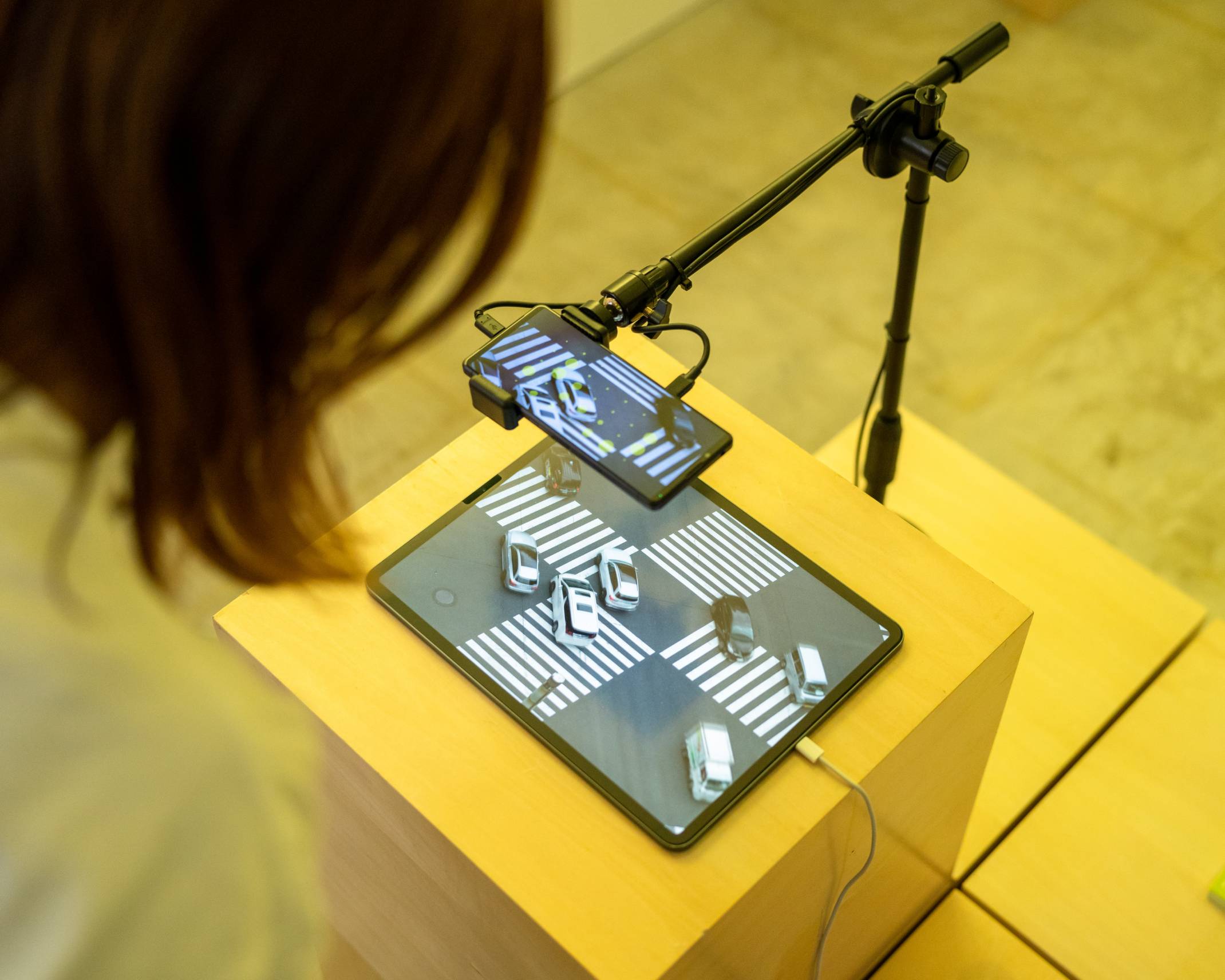 体験の様子。タブレットに表示された交差点の映像をスマートフォンのカメラで検知しているところを覗き込んでいる。