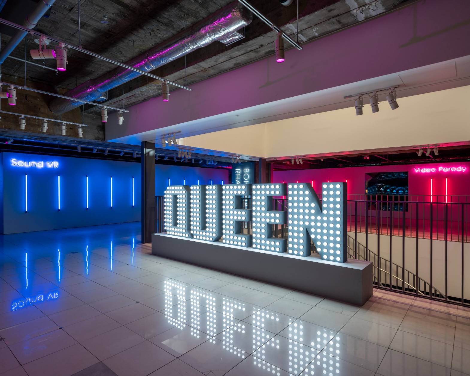会場の様子。ブルーやピンクのLEDに照らされた空間に、QUEENの文字が電飾によって形作られている。