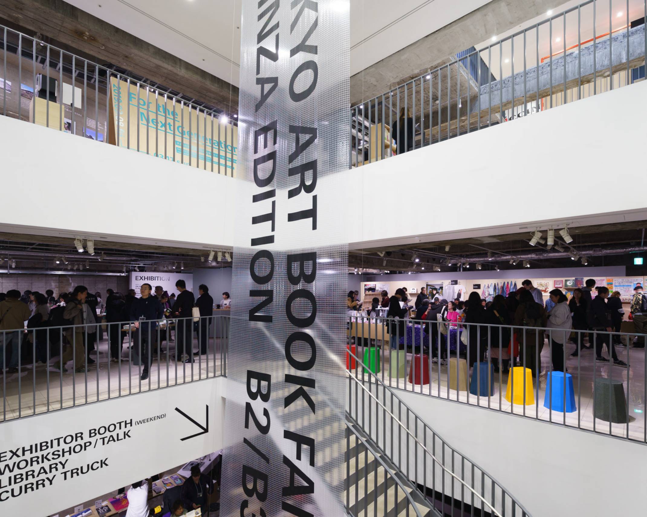 会場の様子。地下吹き抜けに垂直バナーが掲出された会場の各フロアには多くの来場者が集まっている。