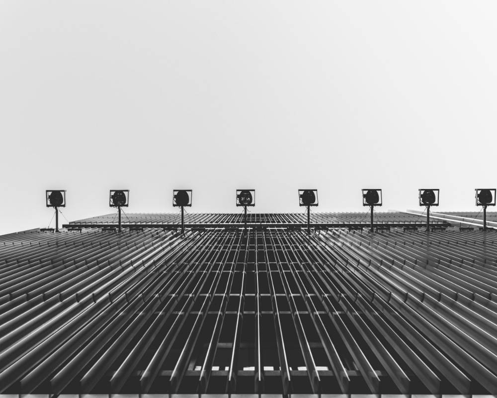 外観（モノトーン）。地上から仰ぎみる外壁には、エッフェル塔を想起させる断面のルーバーが等間隔に並んでいる。