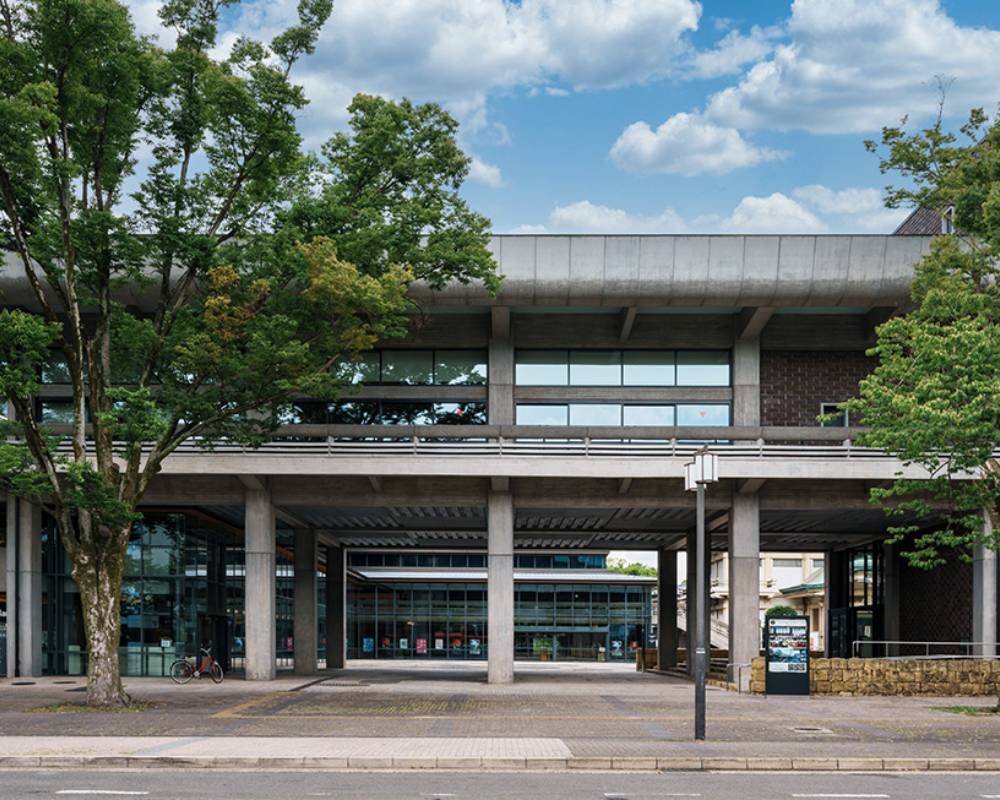 外観。横長な建物をくぐり抜けた先にはガラス張りのエントランスがある。