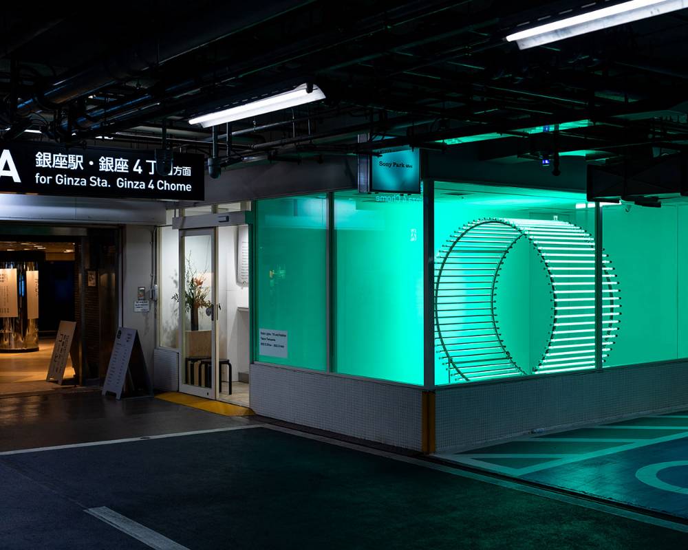 外観。展示スペースに緑色の光を纏う円柱型のオブジェが置かれている。