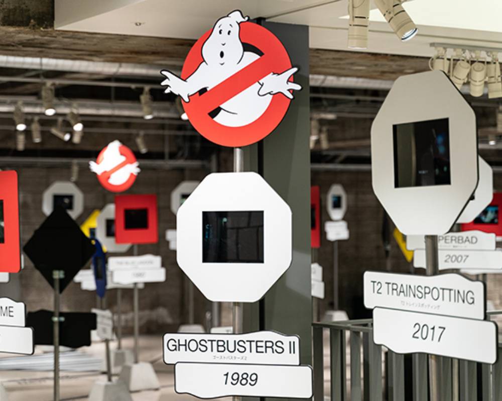 展示の様子。交通サインをモチーフにした展示モニターには、映画の作品名と年代が掲出され、ところどころに"ノーゴースト"マークも見える。