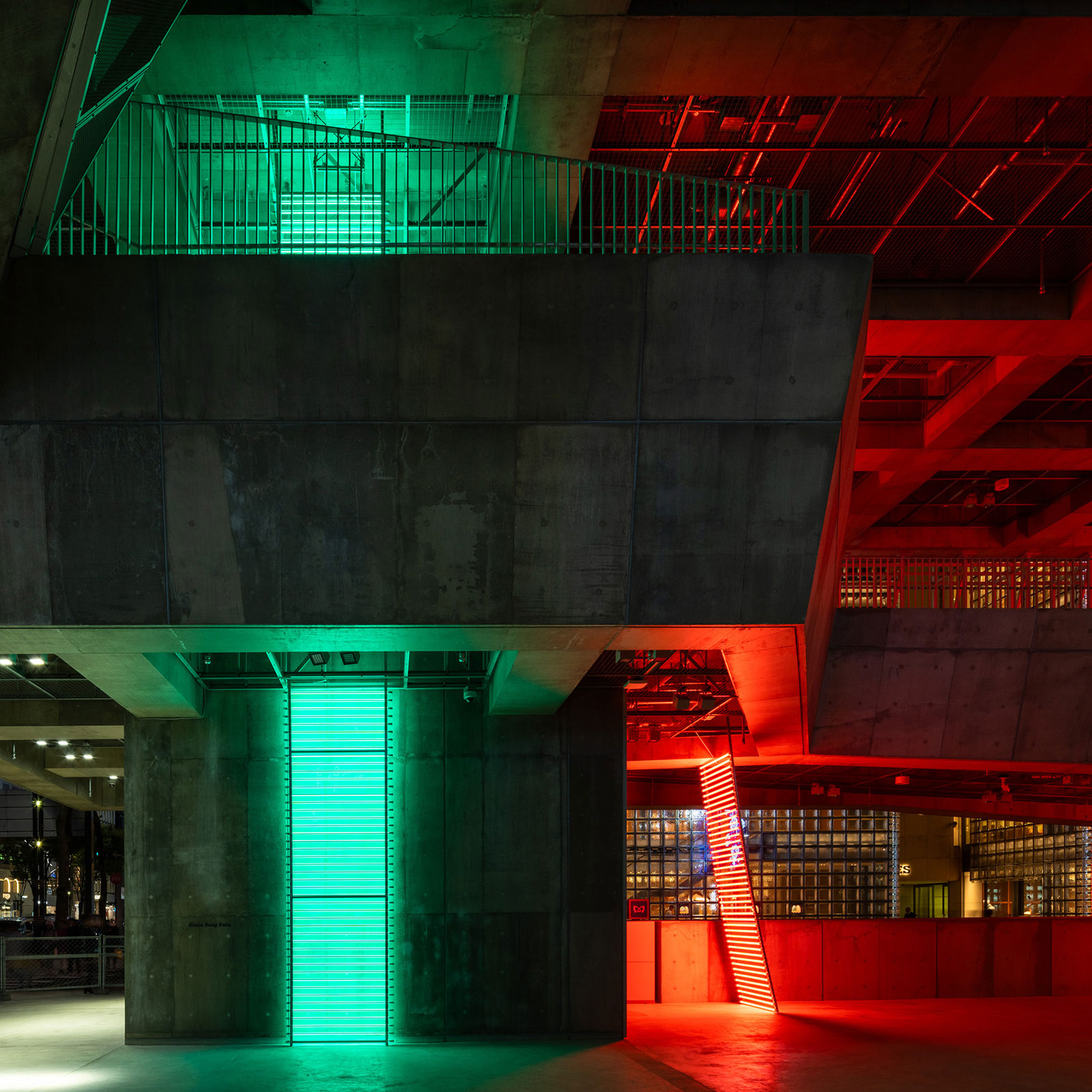 Exhibit. Green and red lights are shining in the concrete architectural space. 