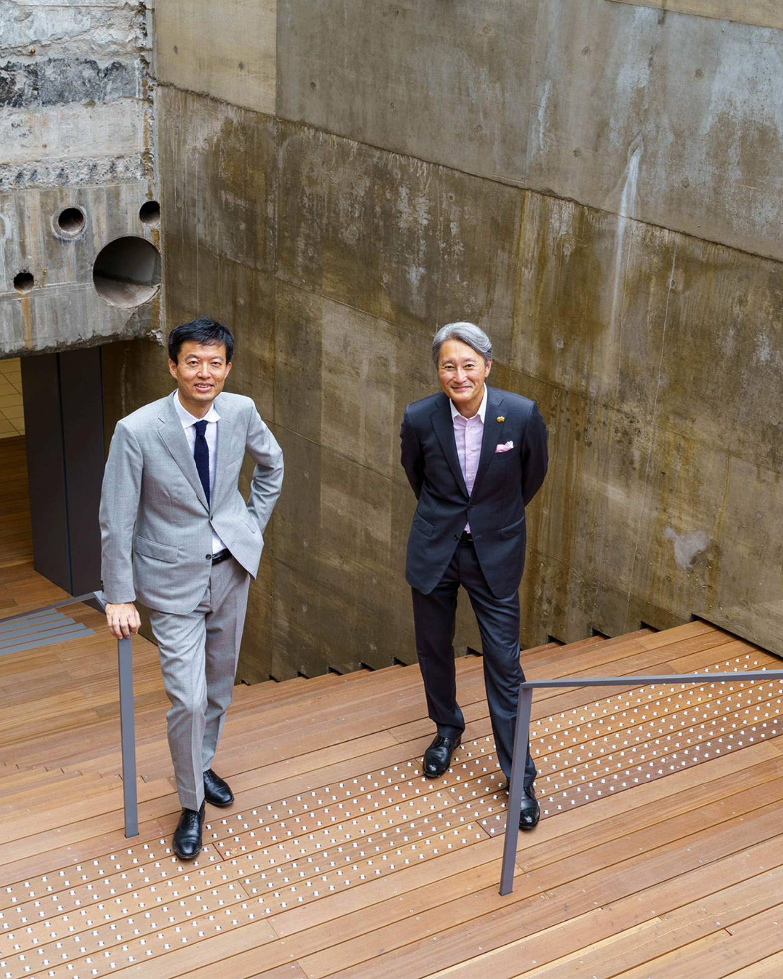 外観。平井一夫と永野大輔が地上から地下へ降りる階段に立っている。