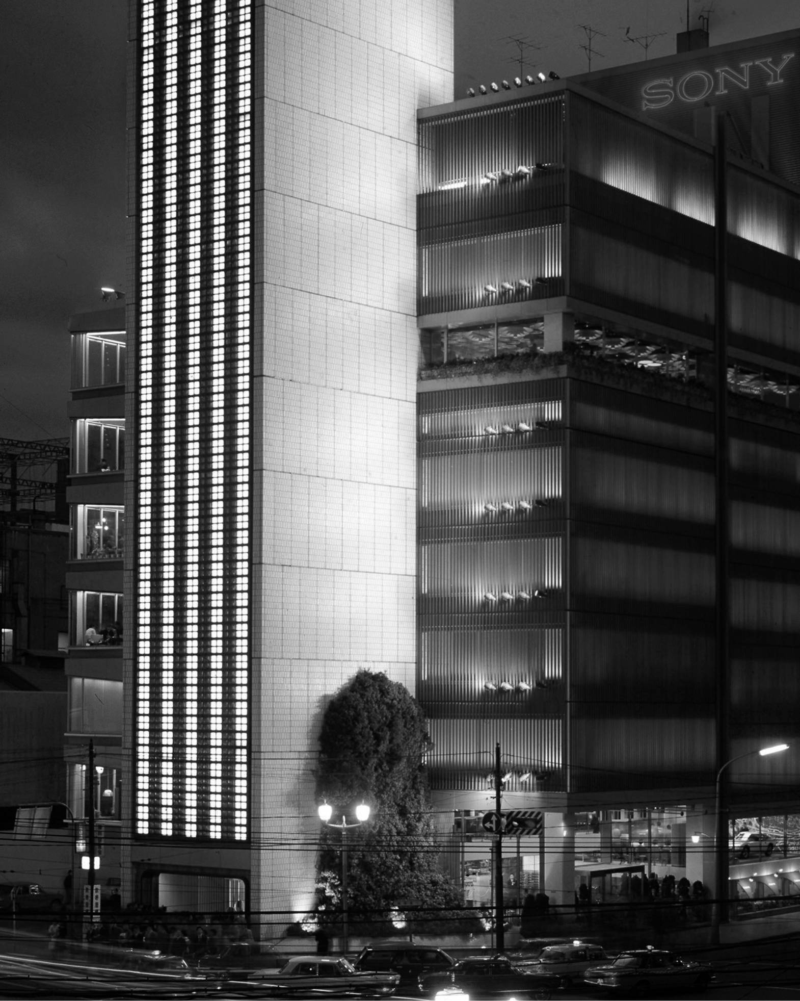 俯瞰風景（モノトーン）。創業当時の夜のソニービル。地上の角地に大きな木が立っている。